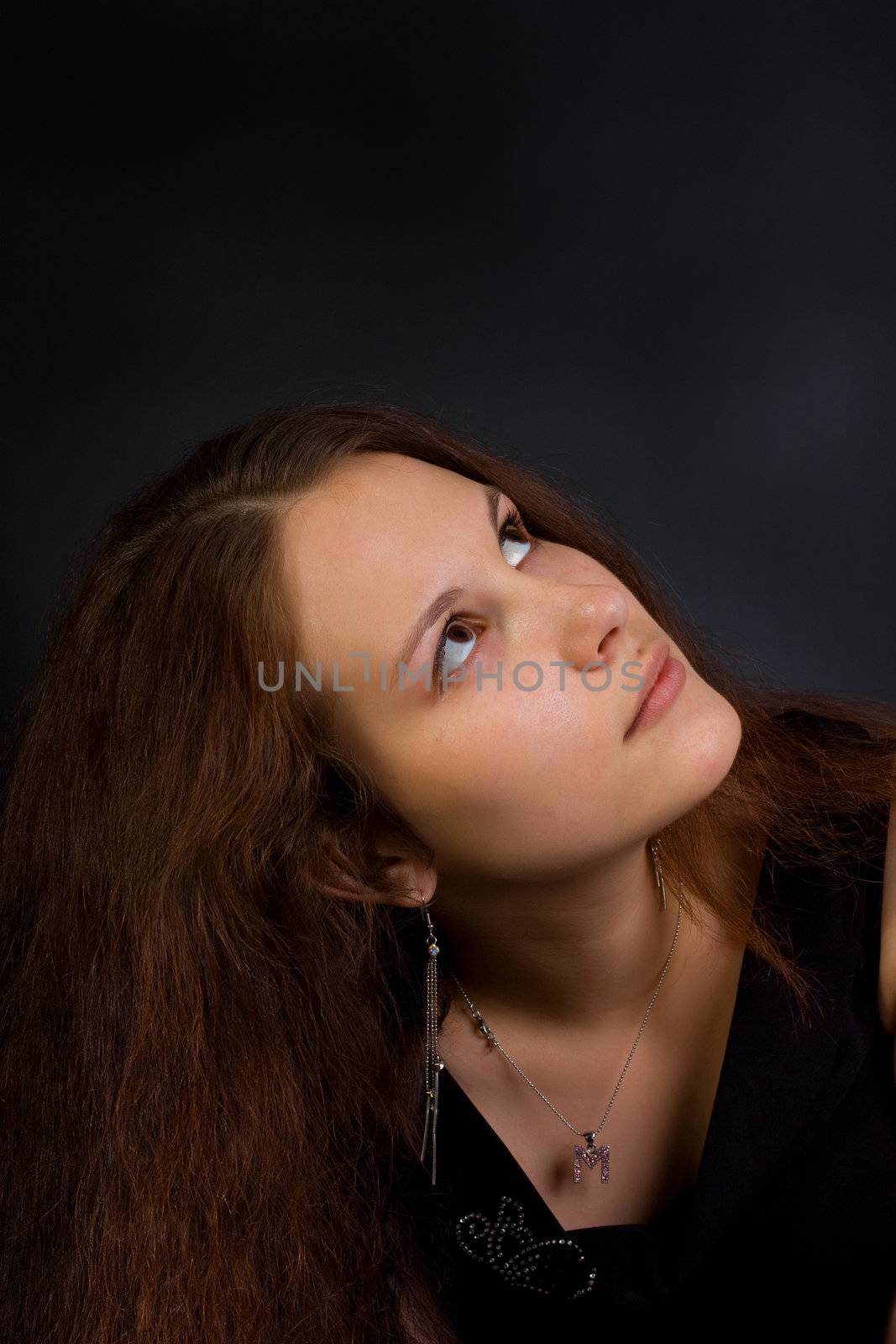 Young woman looking to up. Dark background