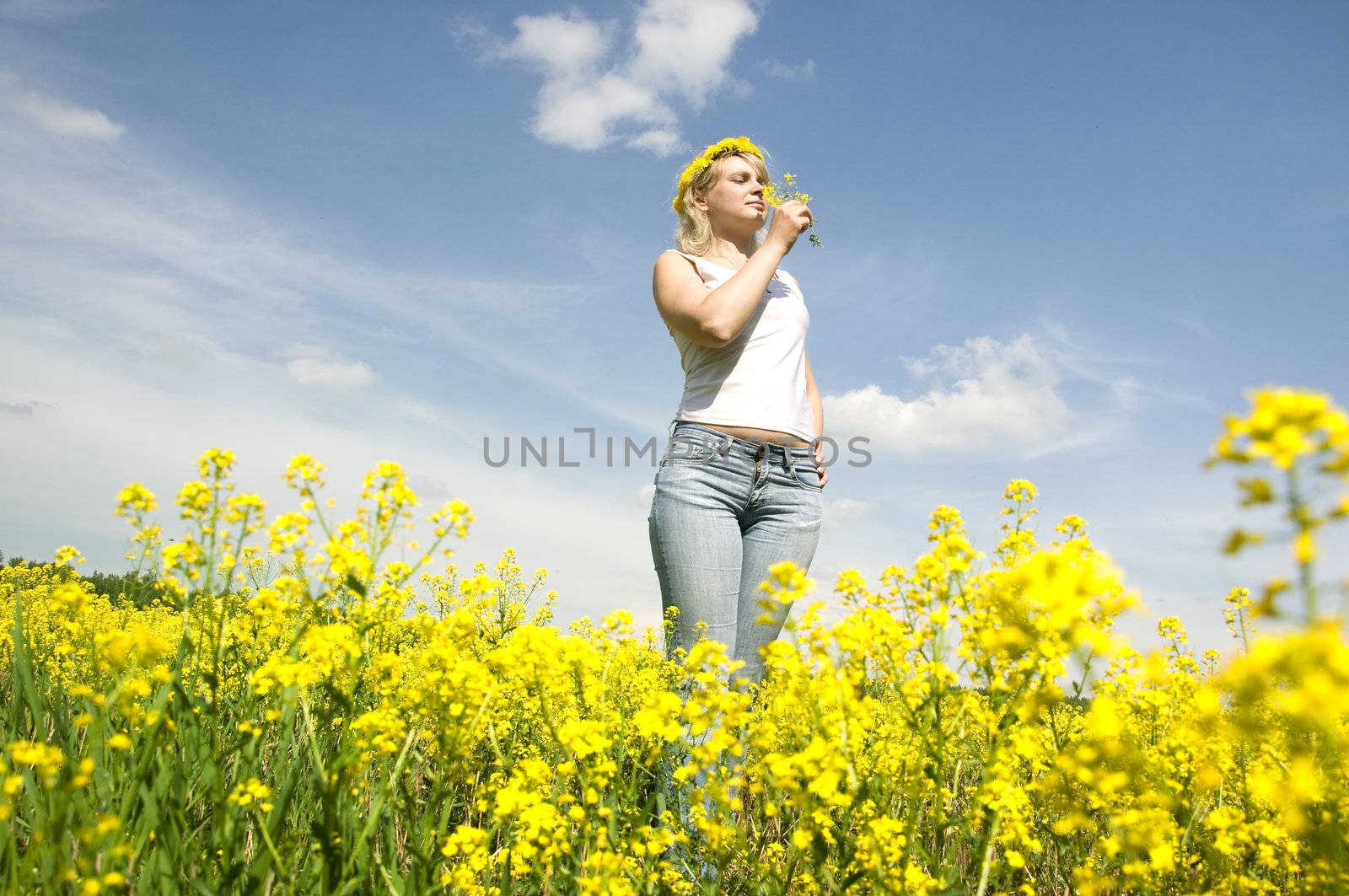 cute young blond woman outdoor in a yellow field wreath on head enjoy in nature