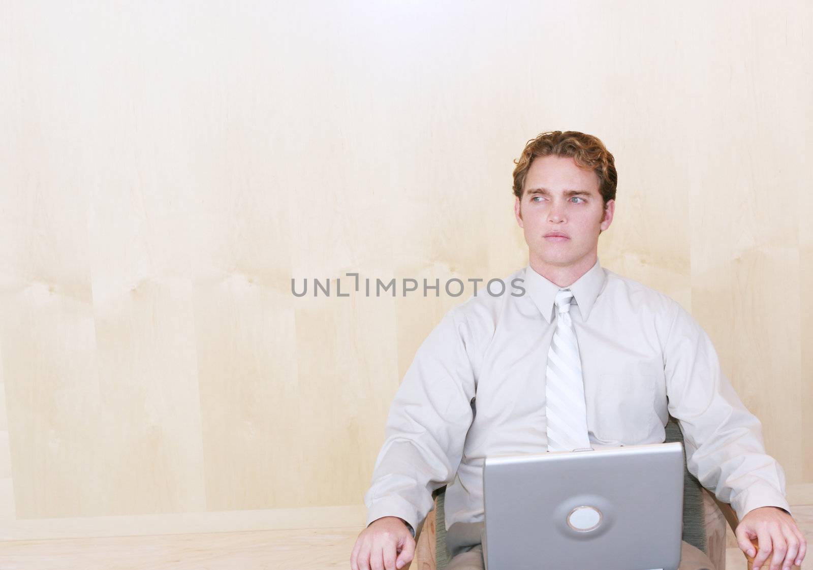 Businessman sitting in his desk chair with his laptop computer in front of him thinking about business solutions wearing business casual clothes