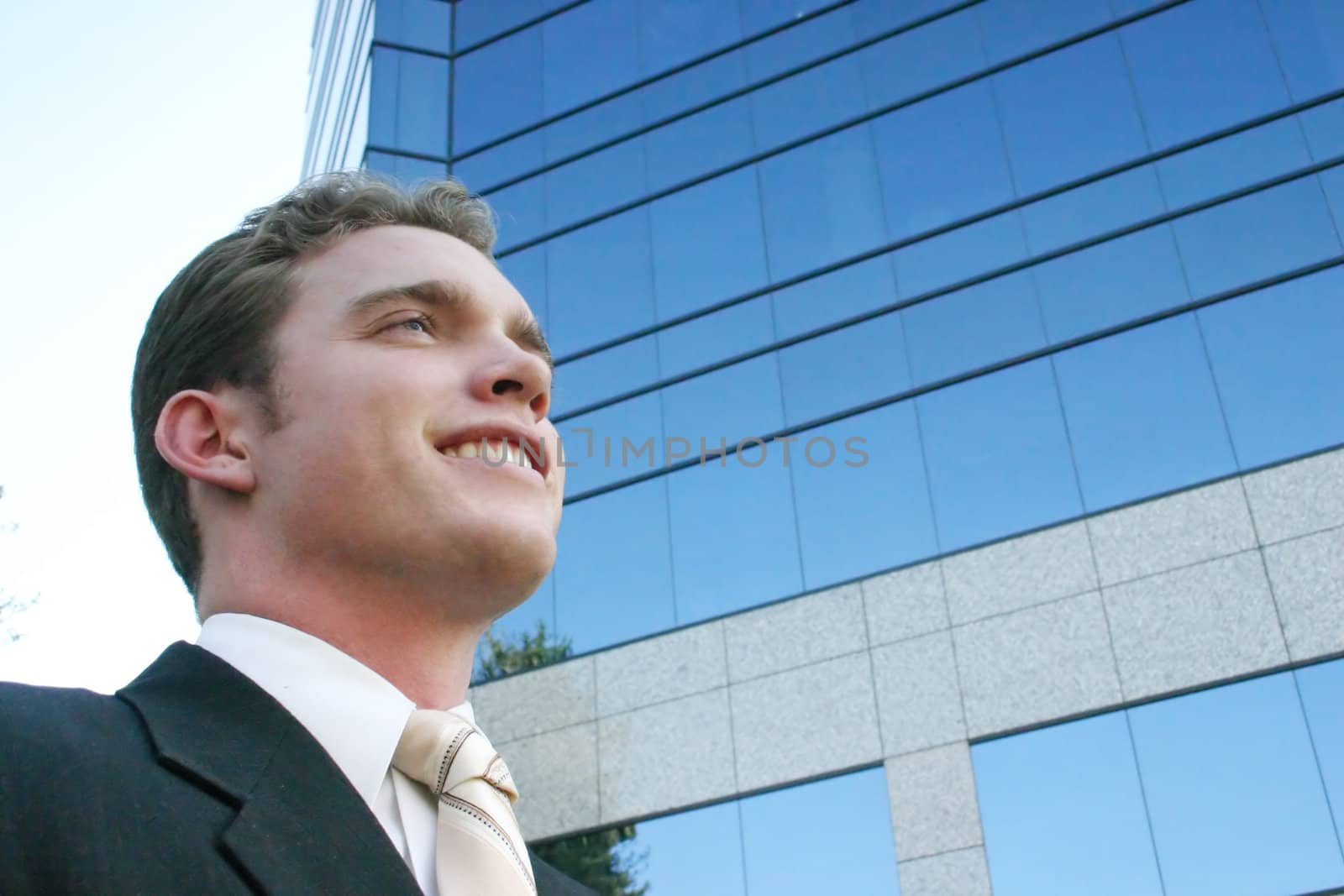 happy businessman standing in front of a business building with a smile on his face looking ahead 