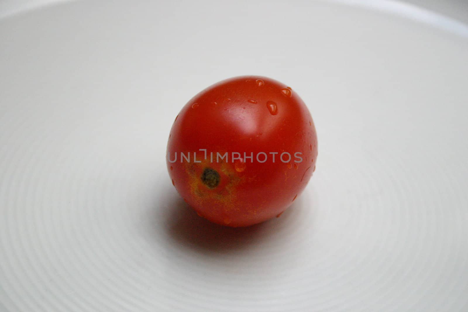 a tomato with water drops on a white dish