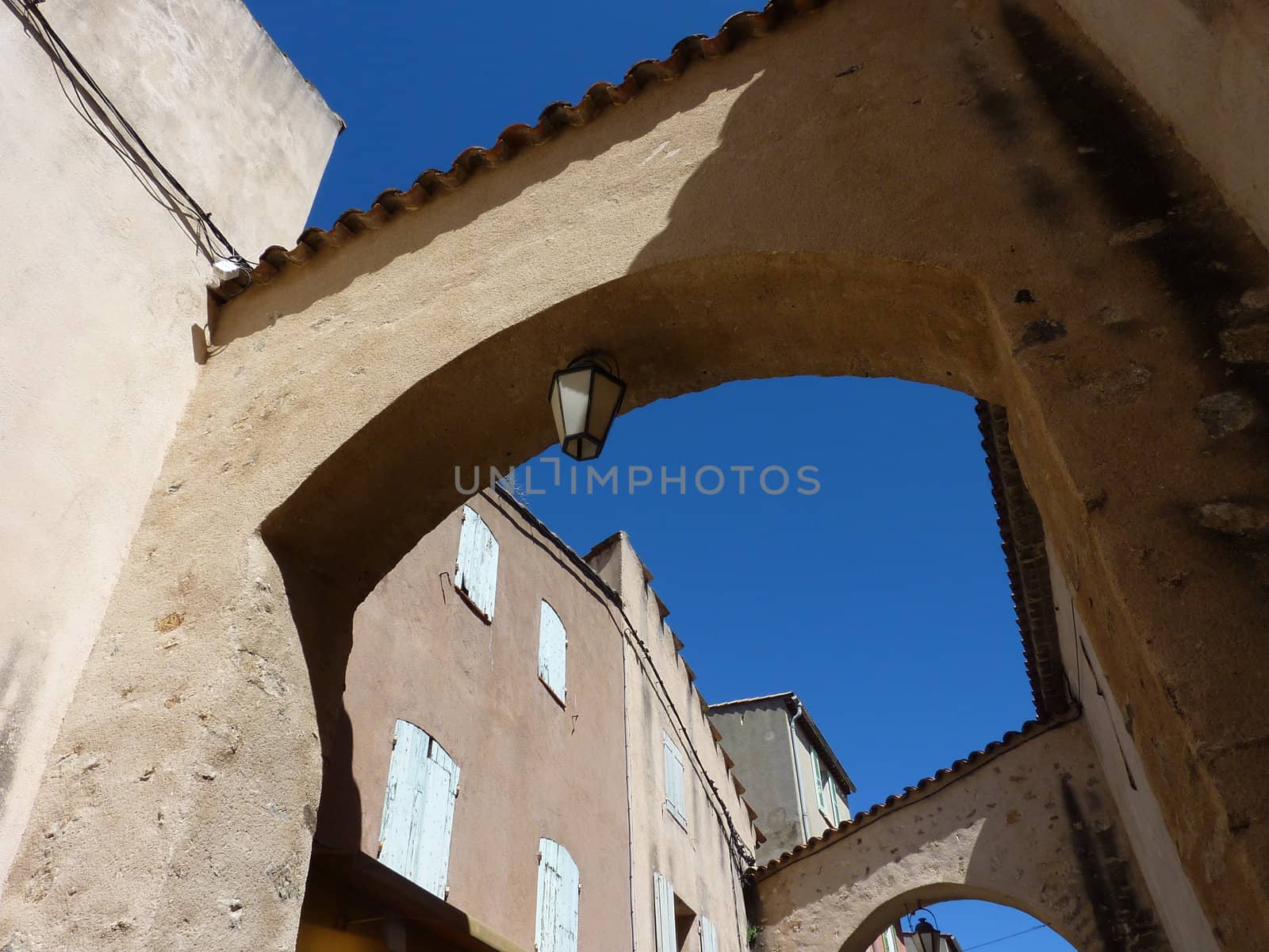 Arch with lamp and buildings with closed shutters in Saint-Tropez, France, by beautiful weather