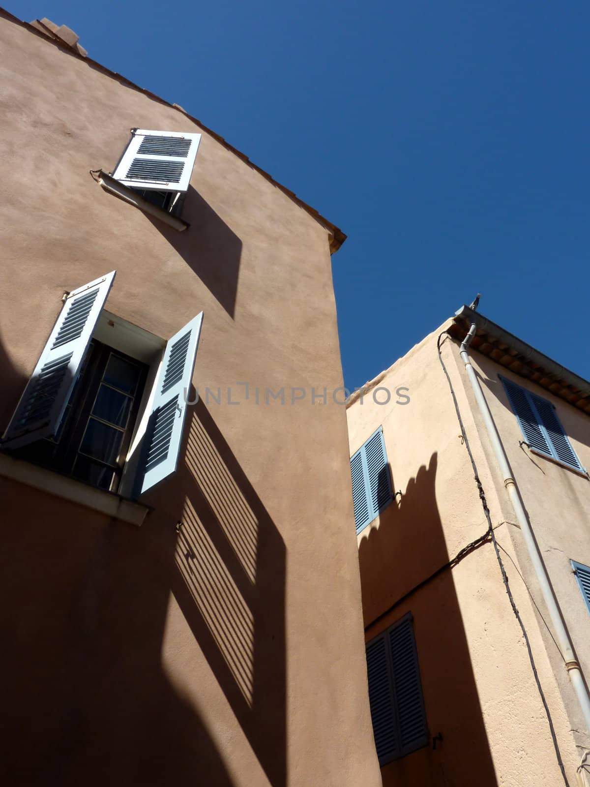 Facades with green shutters and their big shadows in Saint-Tropez, France, by beautiful weather