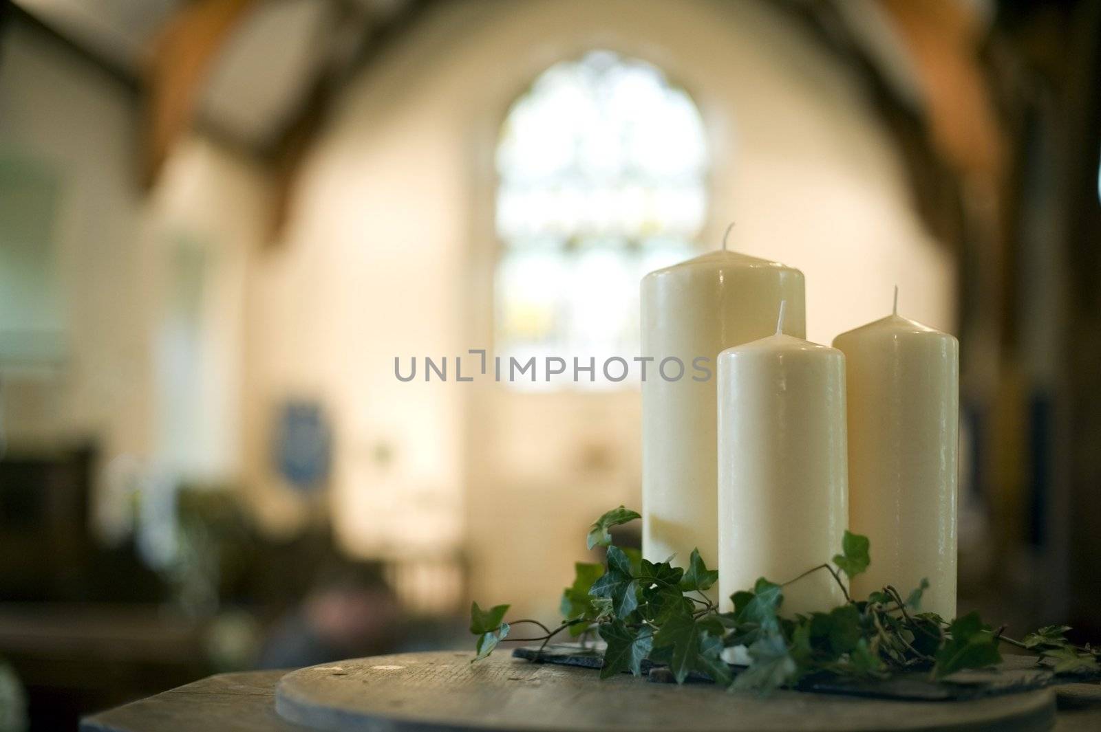 a narrow depth of field image of the interior of a church focusing only on three white candles