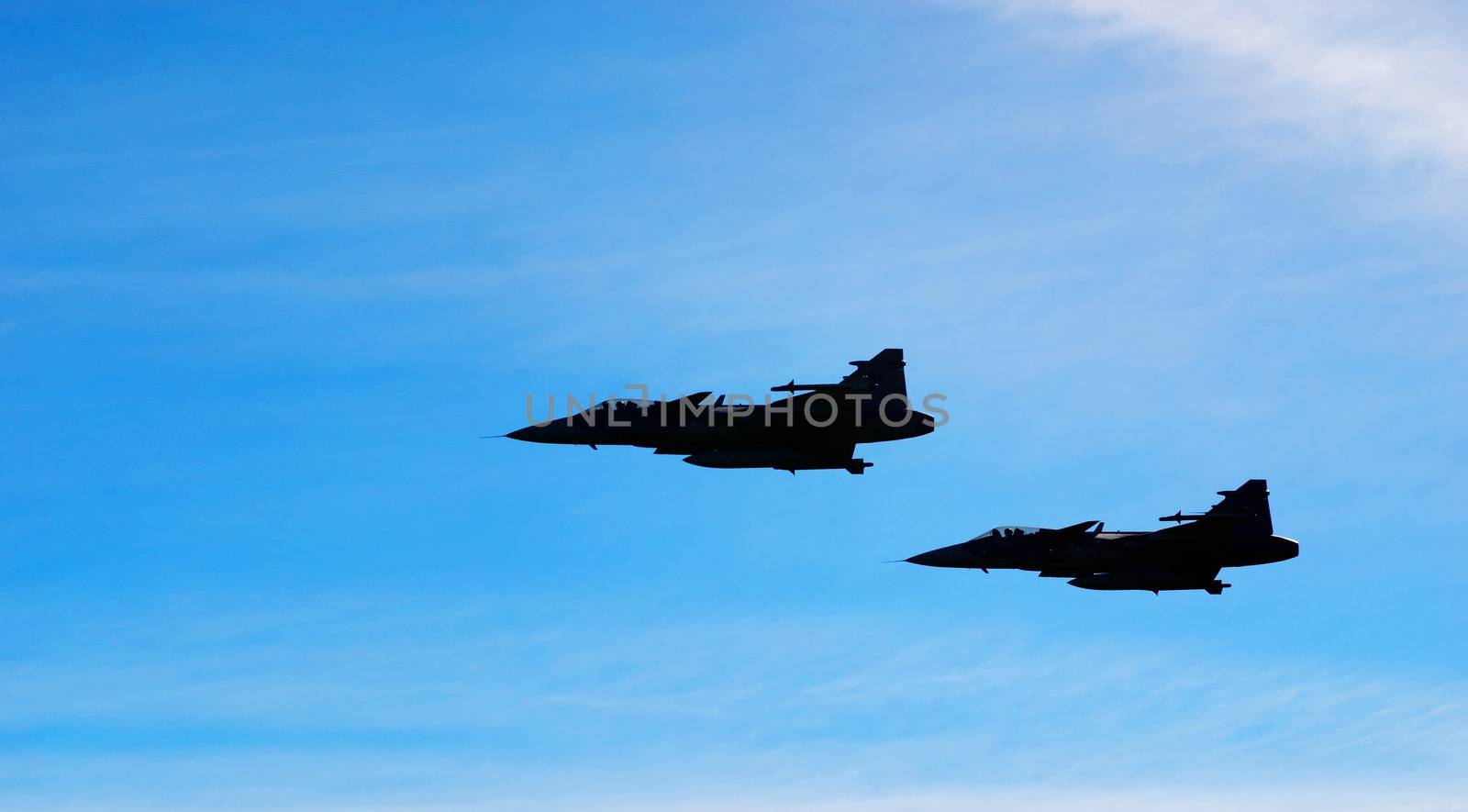 Two aircraft Jas 39 Gripen on blue sky by artush