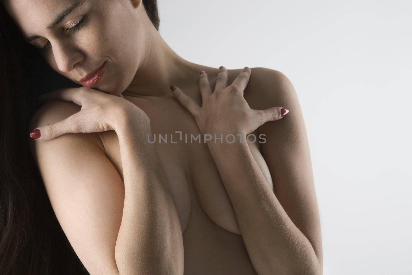 Topless Caucasian woman with arms crossed looking to the side.