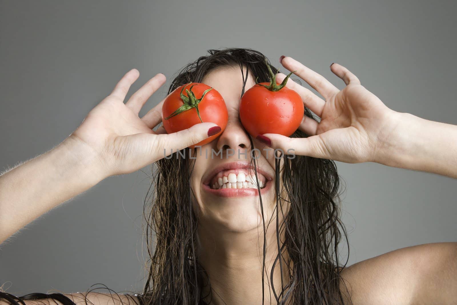 Caucasian woman with tomatoes covering her eyes.