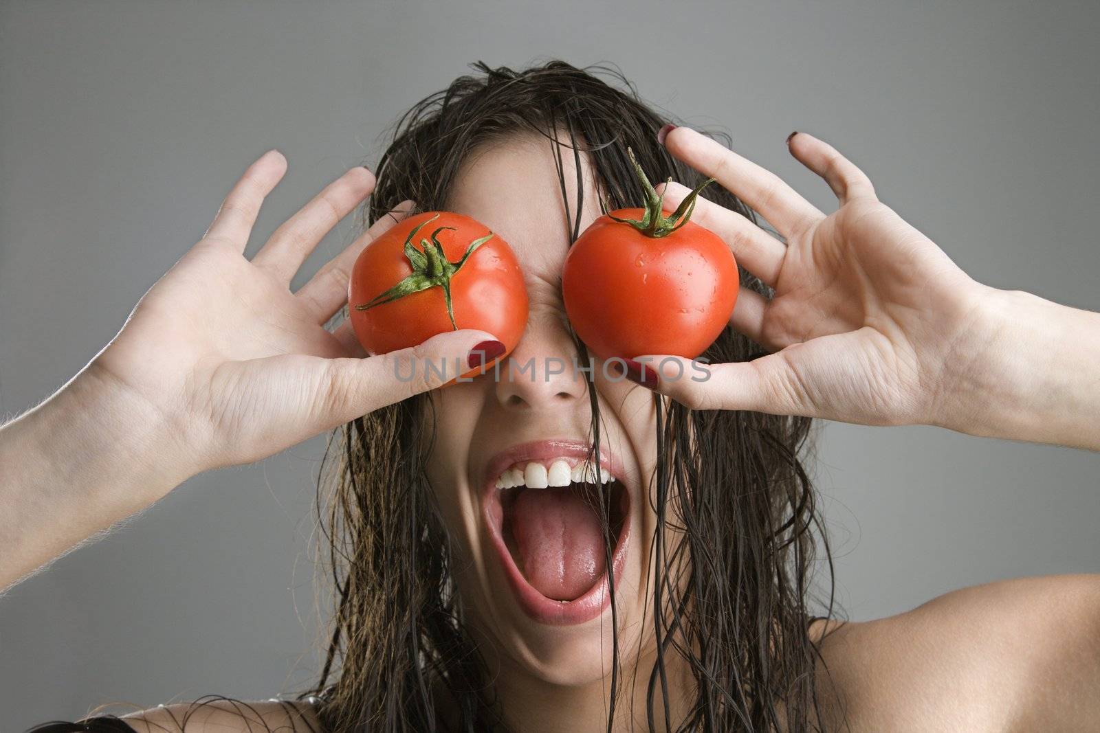 Caucasian woman with tomatoes covering her eyes.