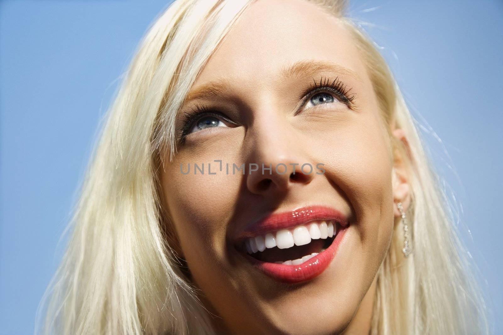 Portrait of attractive blonde Caucasian young adult woman smiling and looking up.