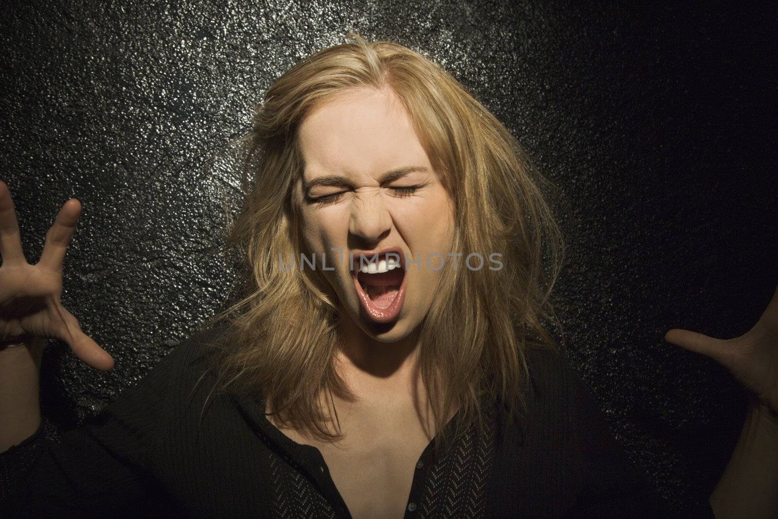 Dark portrait of sexy Caucasian mid-adult woman making fierce roaring expression.