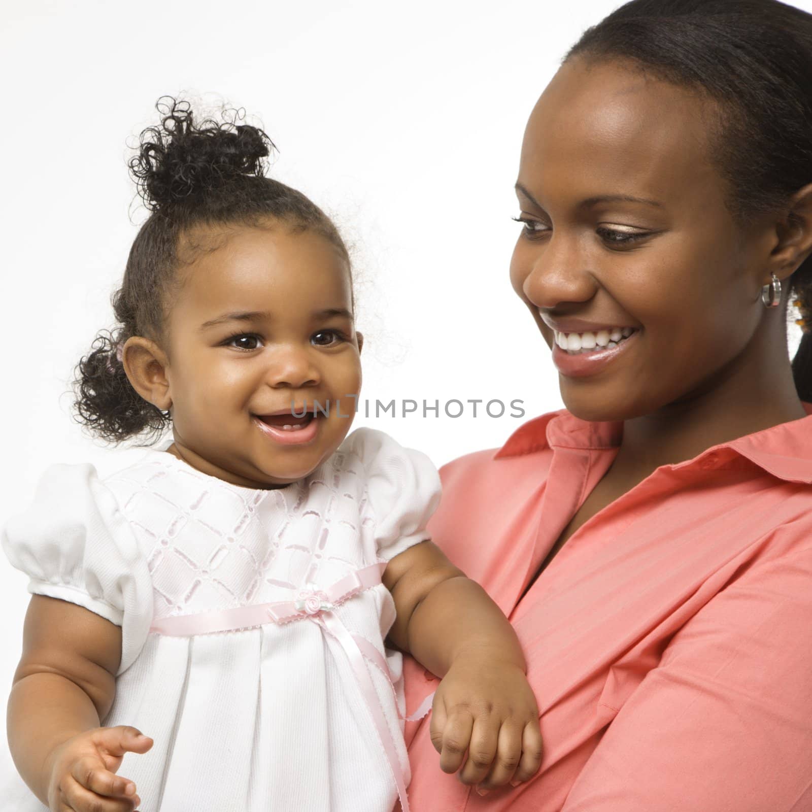 African American woman holding infant girl standing against white background.