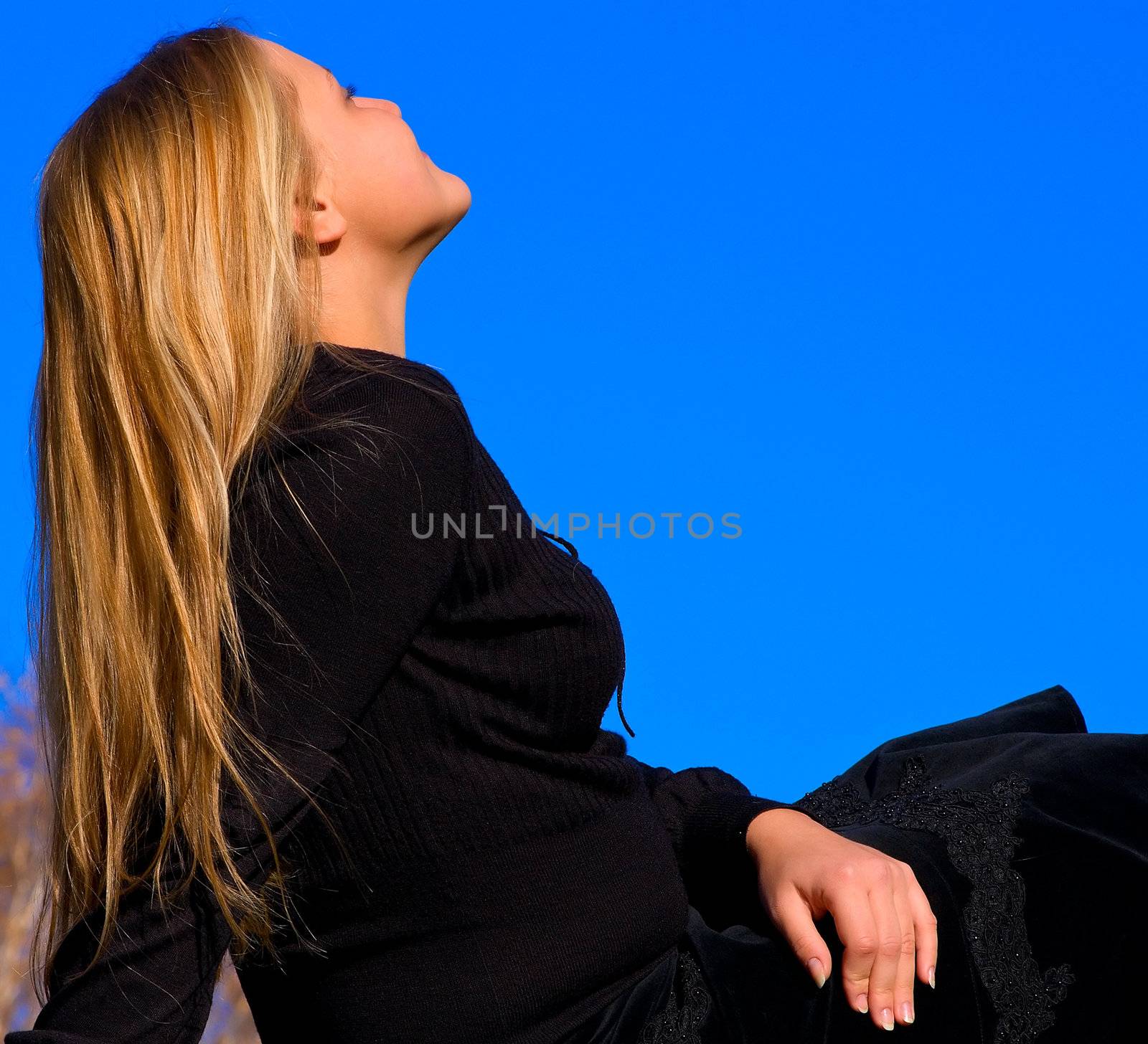 Portrait of the beautiful young girl against blue sky