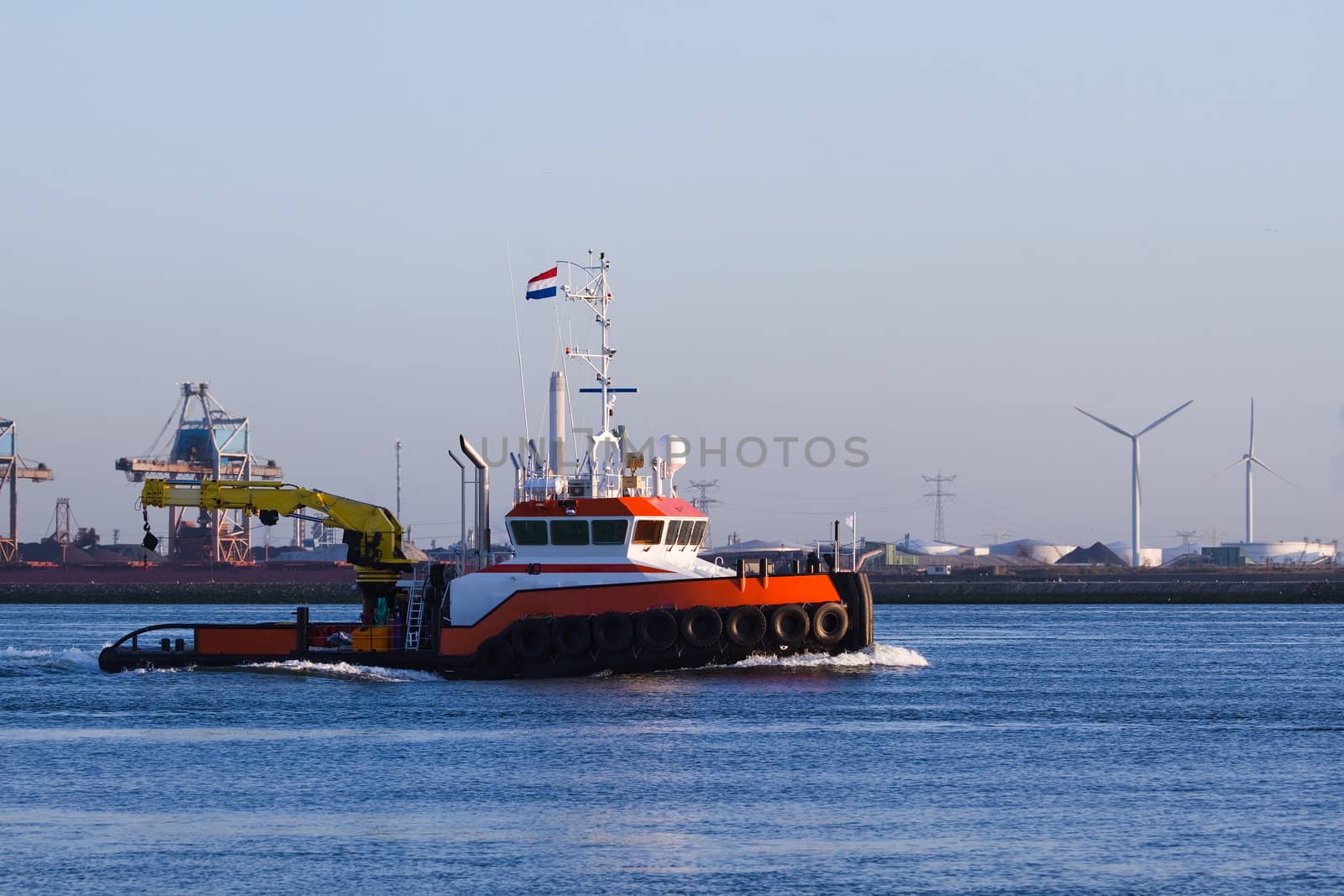 Tugboat with crane passing by on the river in evening light - industrial background