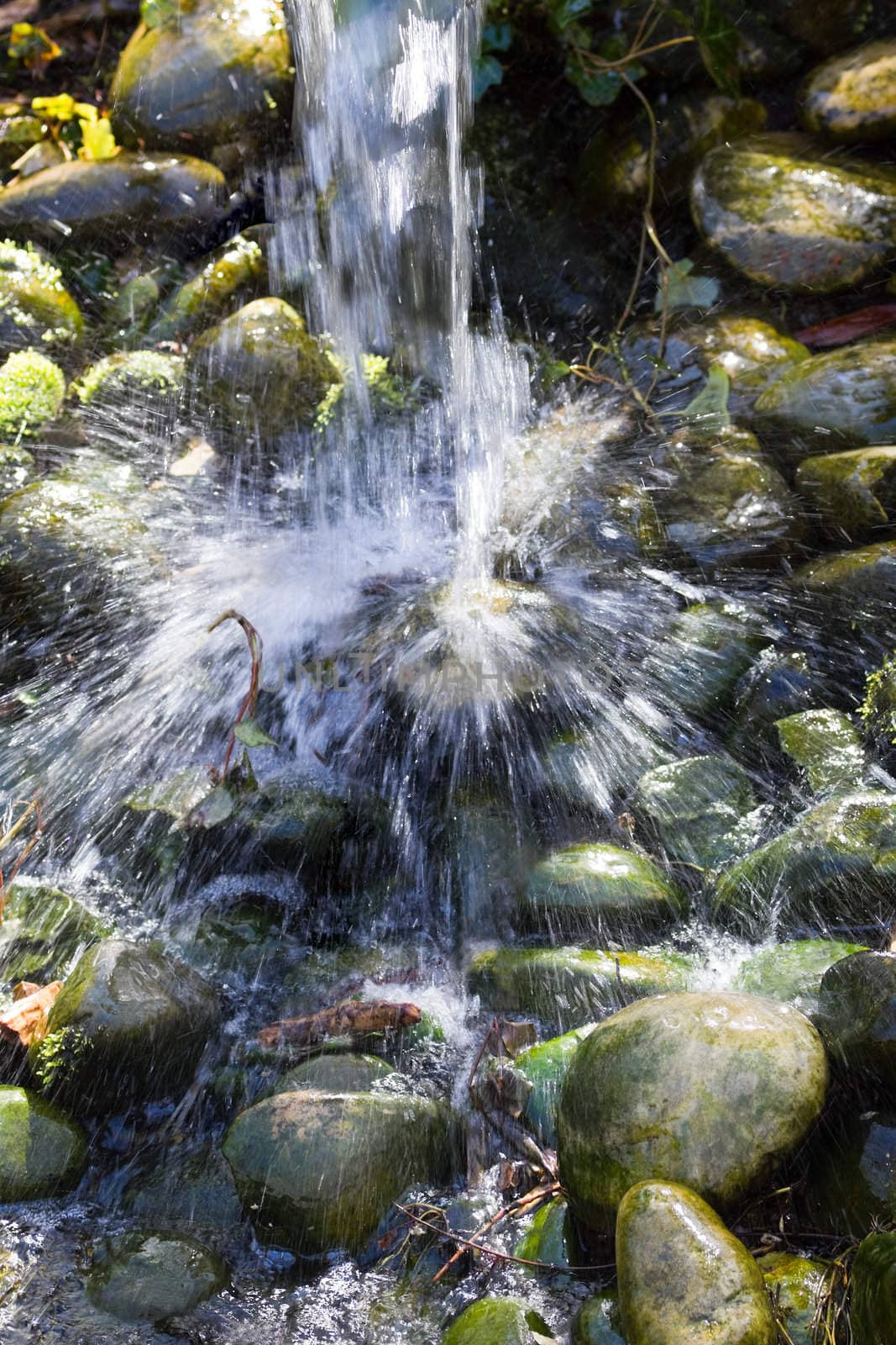 Water is splashing down on boulders from a waterfall