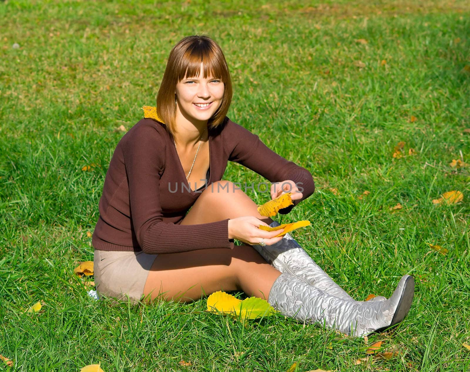 The young girl on green grass in autumn park