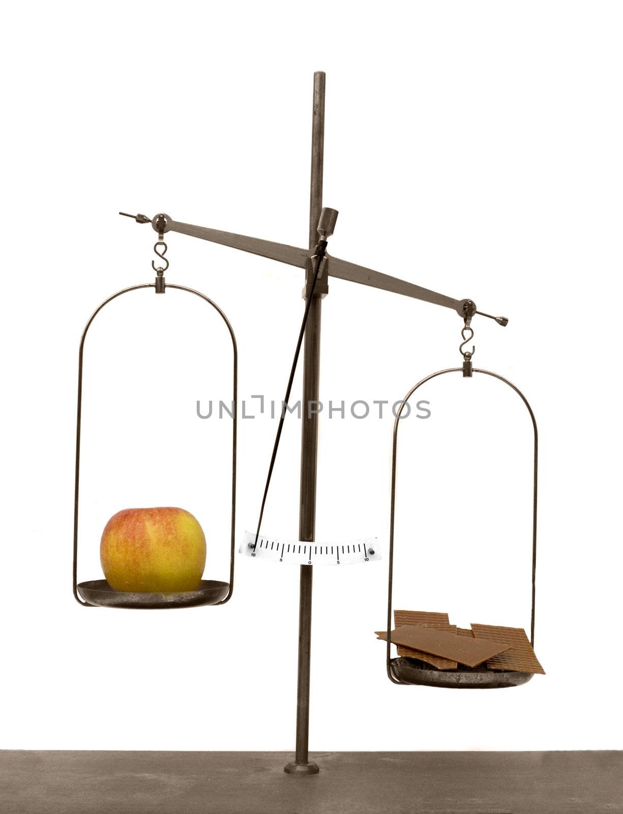 Old scales with apple and chocolate isolated on white background, showing that the apple is the lighter choice