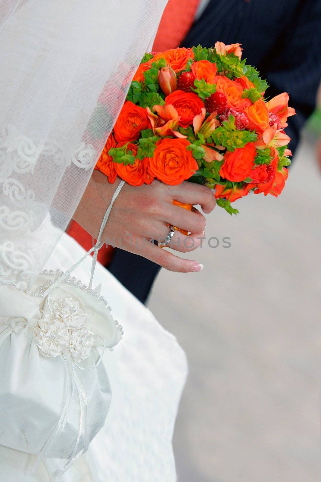Bride in traditional white wedding dress with red bouquet of flowers.