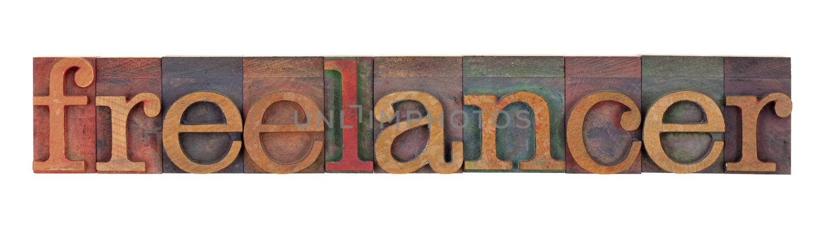 freelancer - word in vintage wood letterpress type blocks stained by color inks, isolated on white