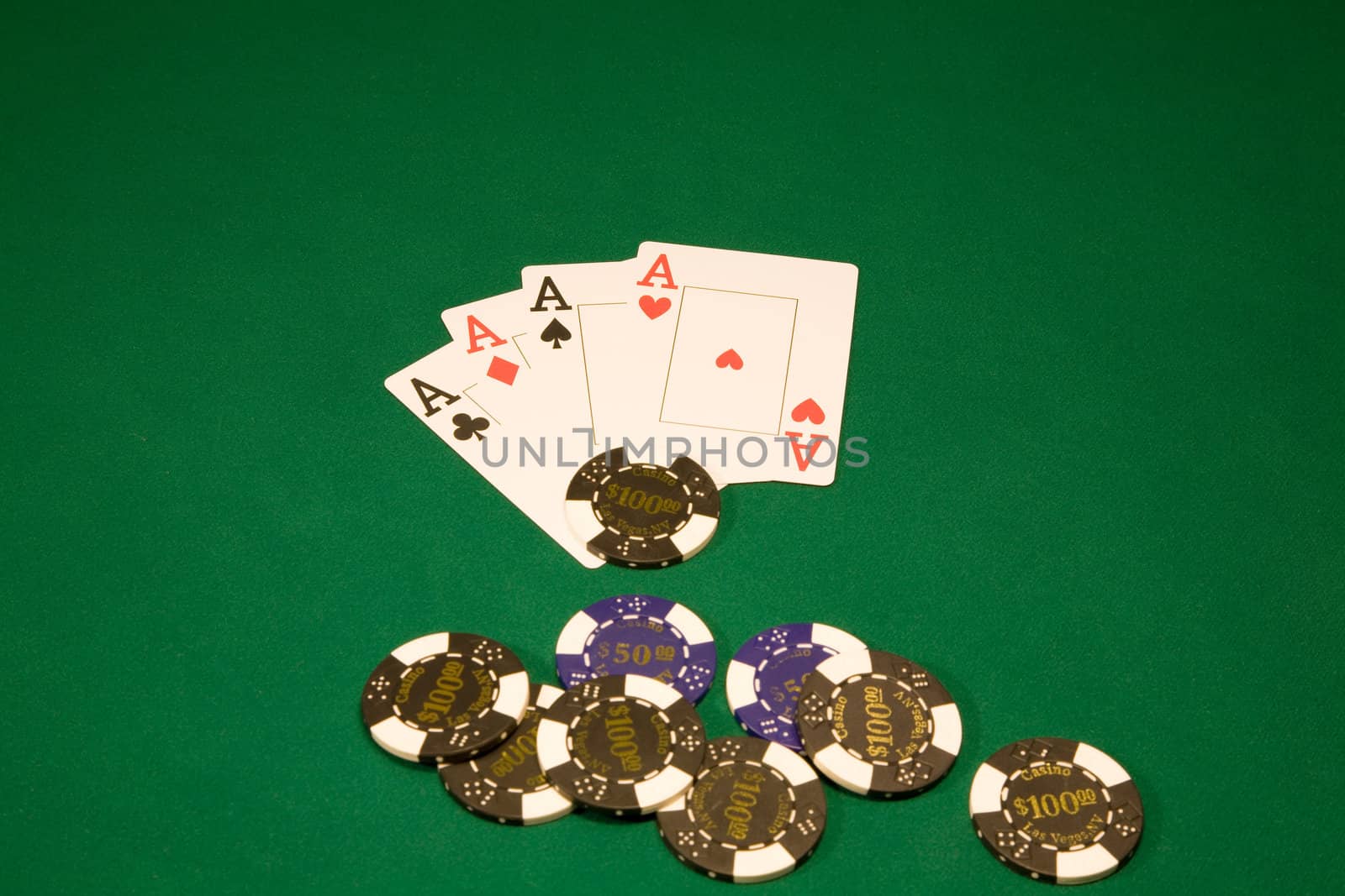 Chips with four aces on the green table in casino