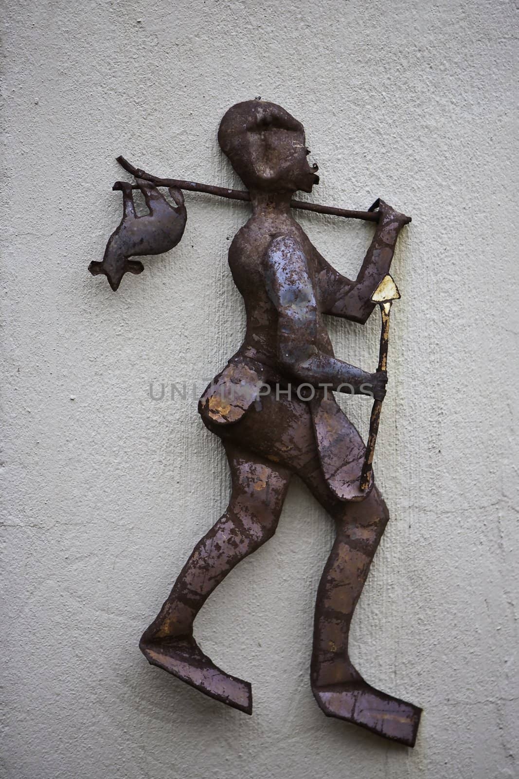 a ruted metal figurine of a native hunter walking with a catch