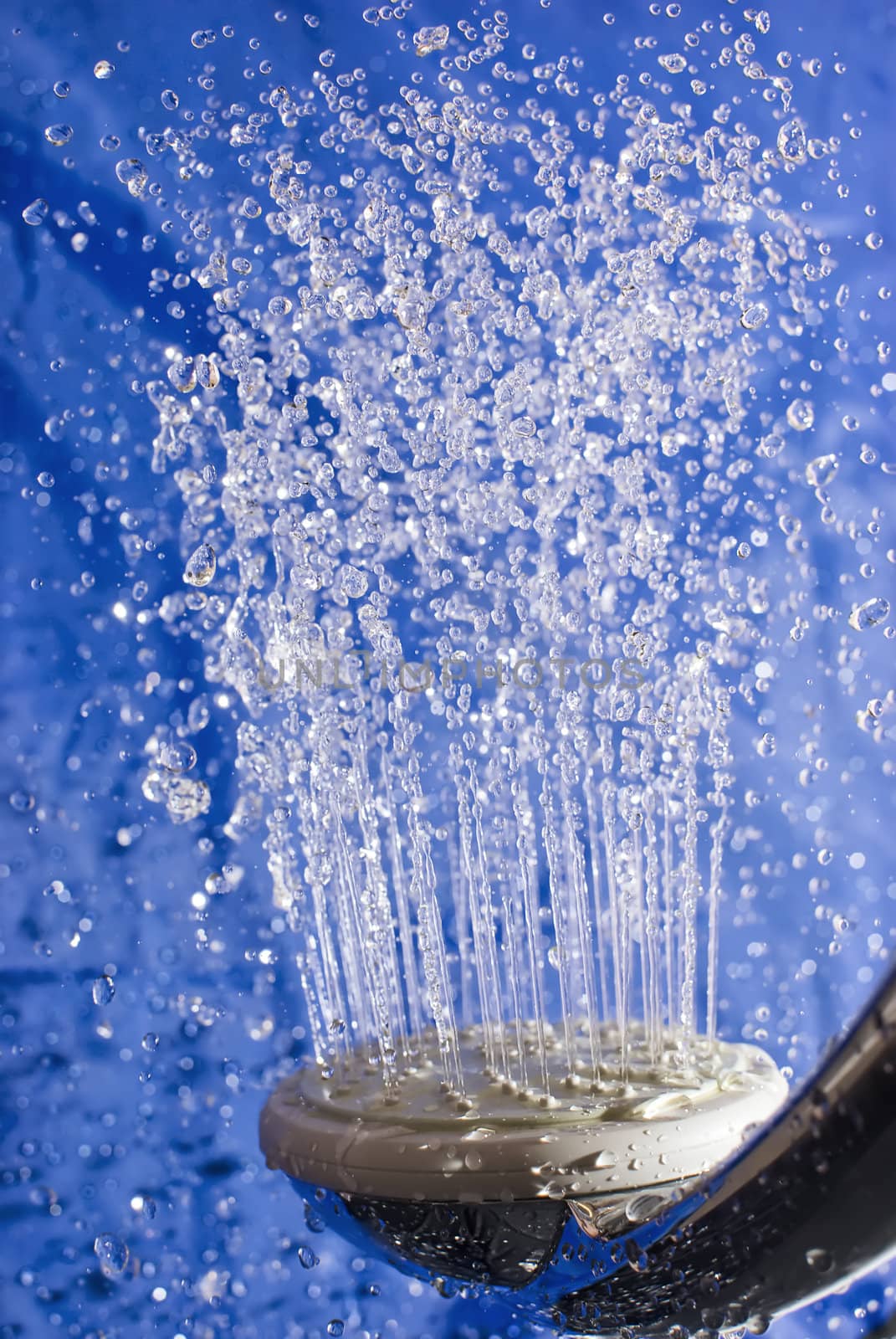 Close-up flying drops of water up and down from the head of the shower in cold and colours