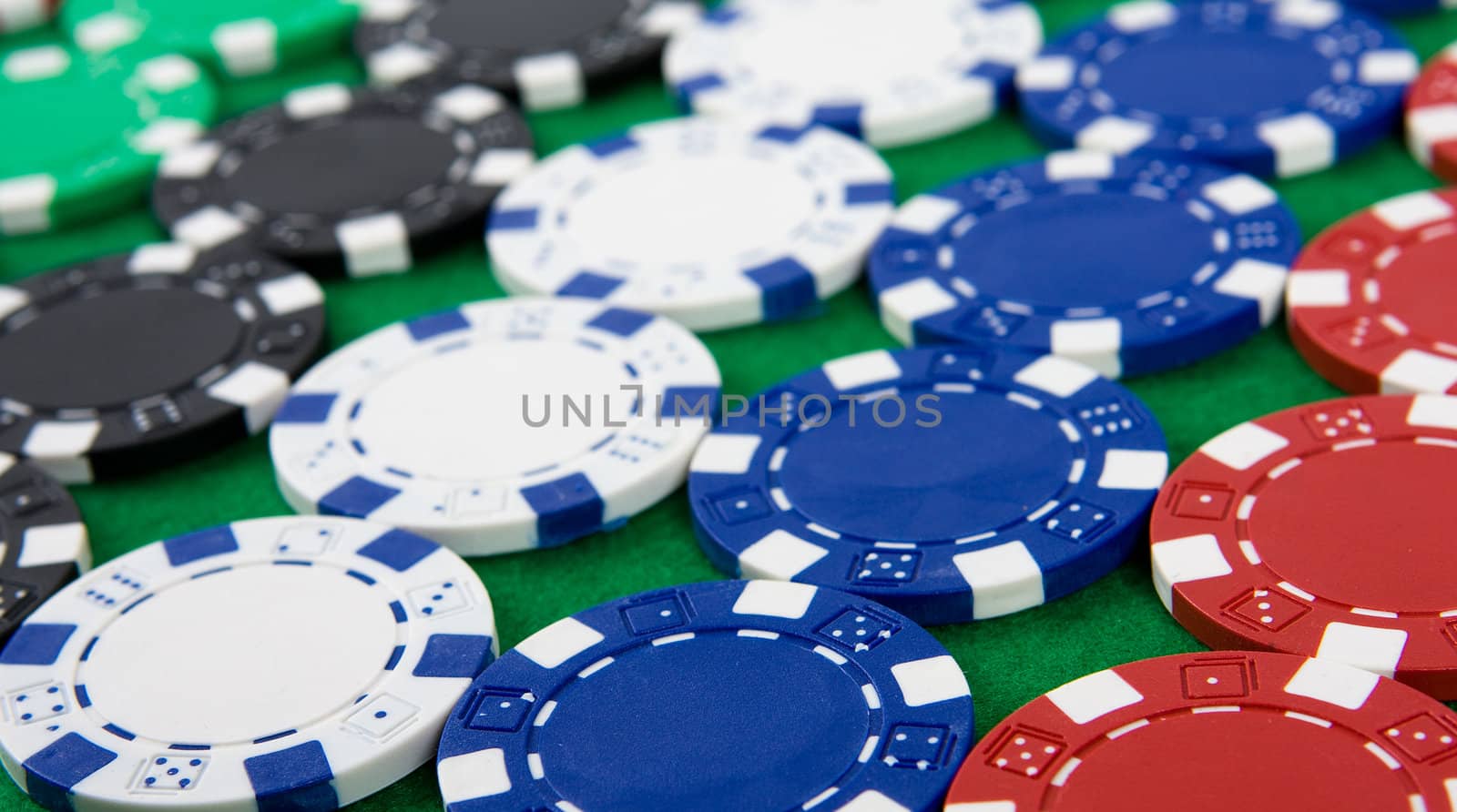 Background of different poker chips on green poker table.