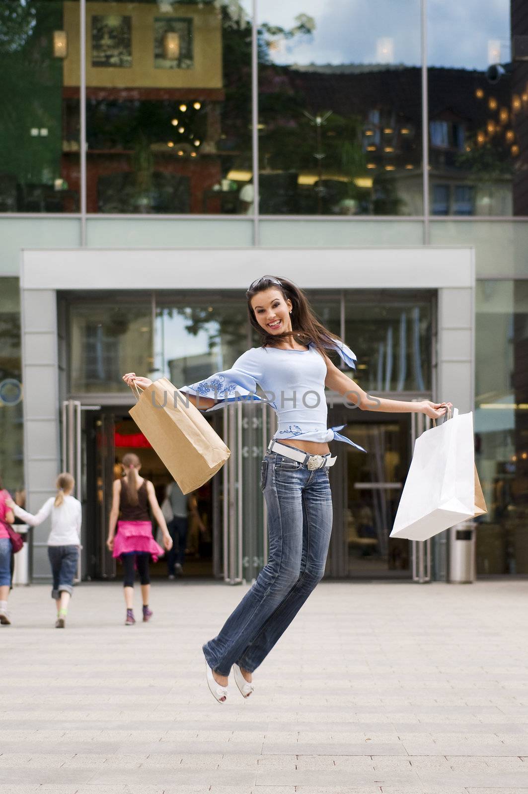 beautiful brunette jumping with her shopping bags after a hard day in commercial center