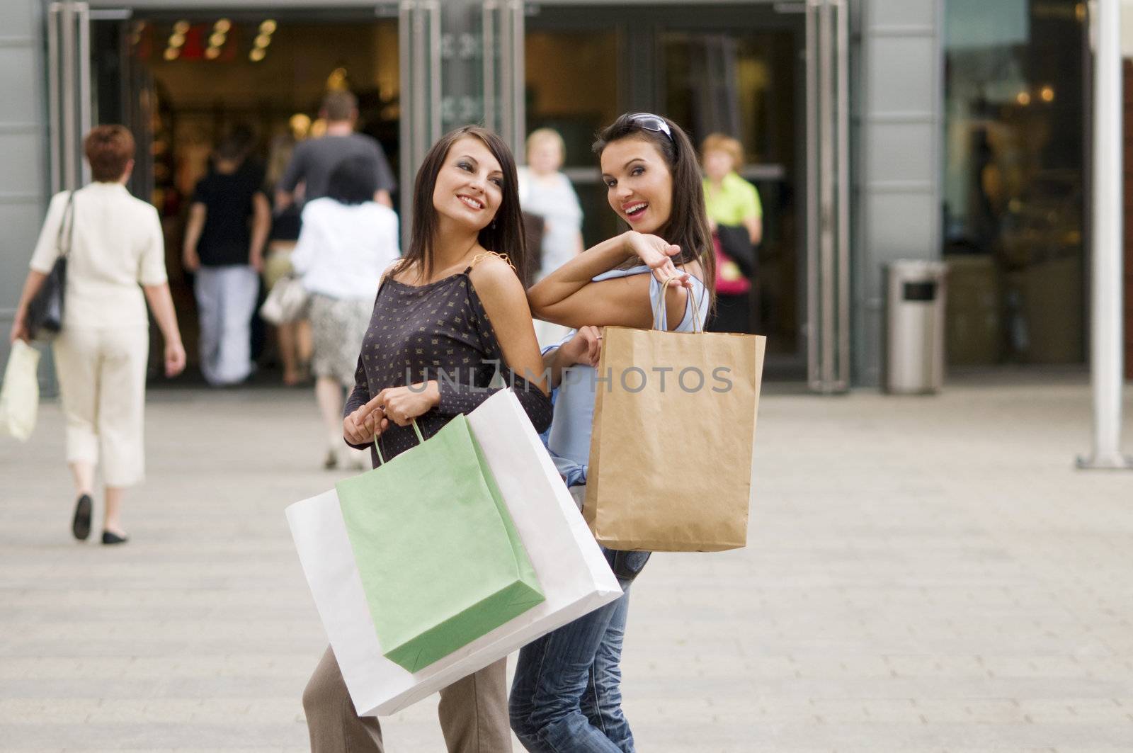 two girls just outside of commercial center with her purchases in bags
