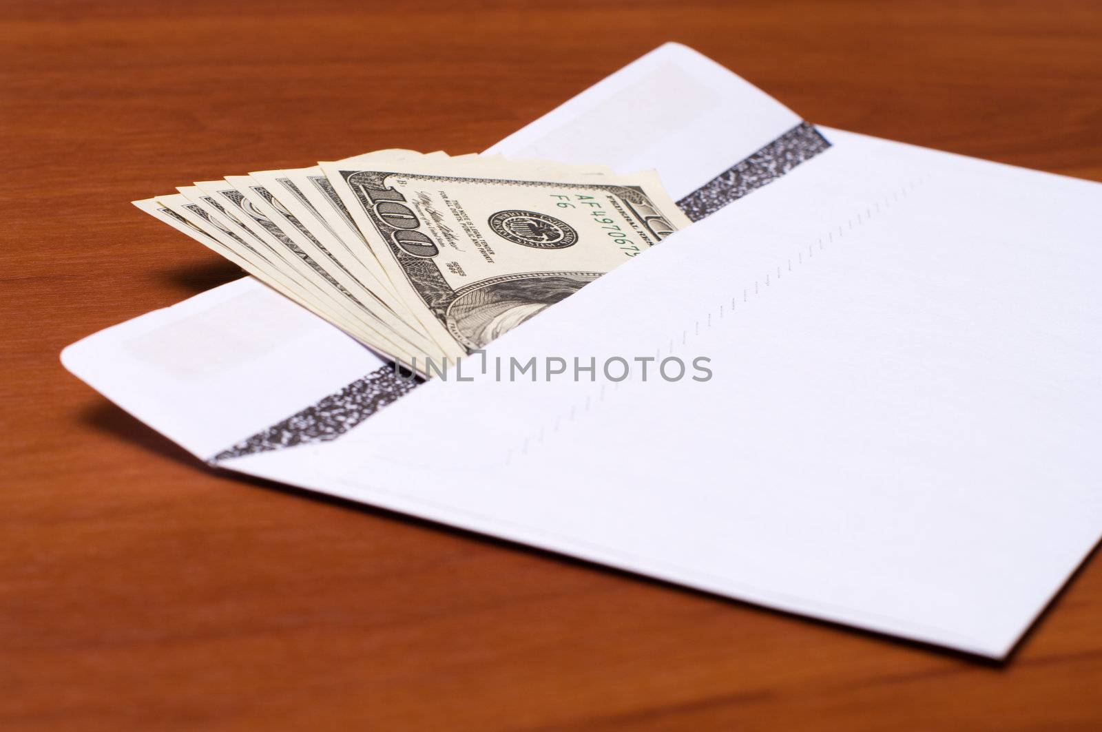 Dollar bills in a white envelope on the office desk.