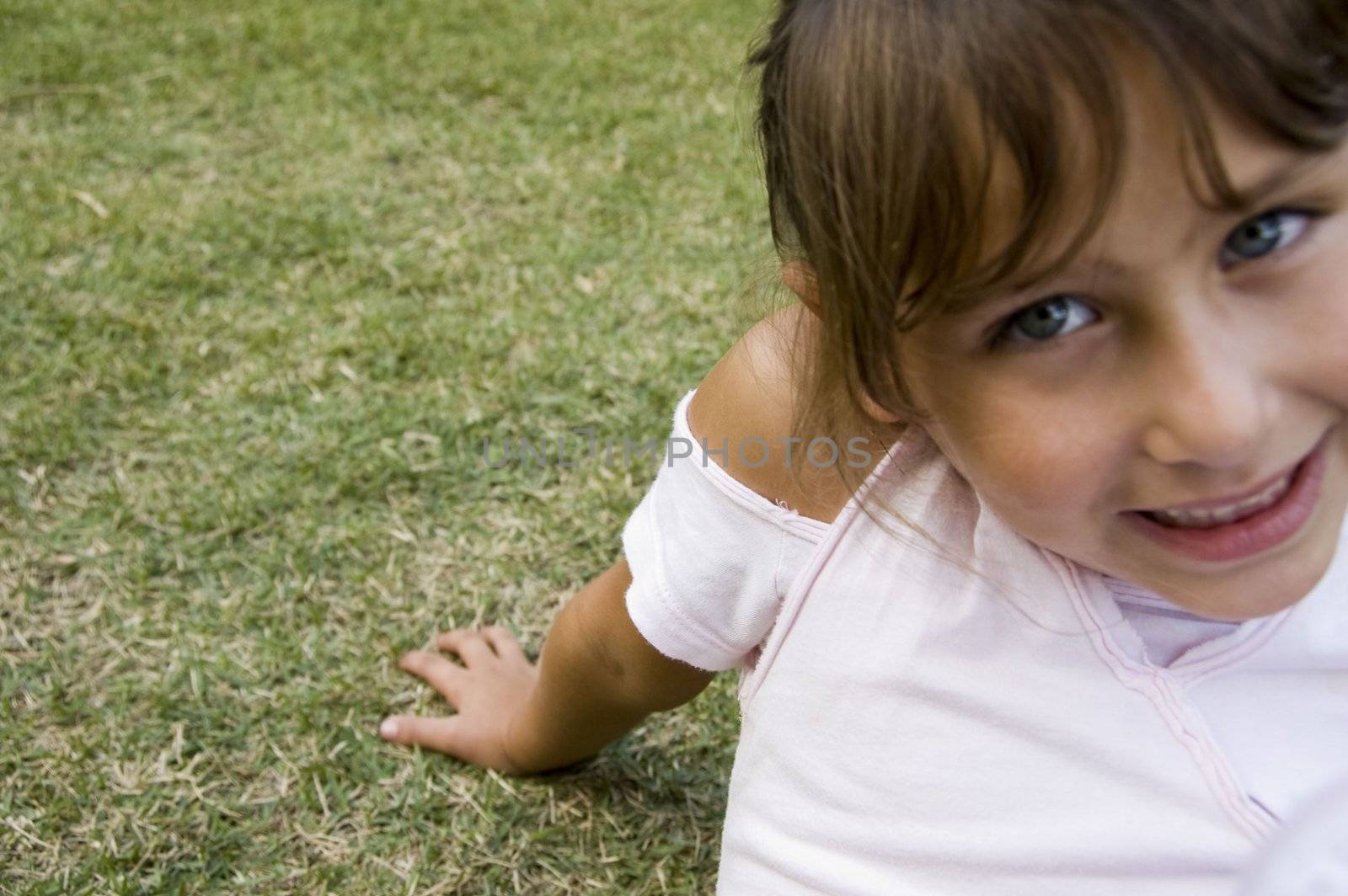 close view of smiling little girl sitting on  grass