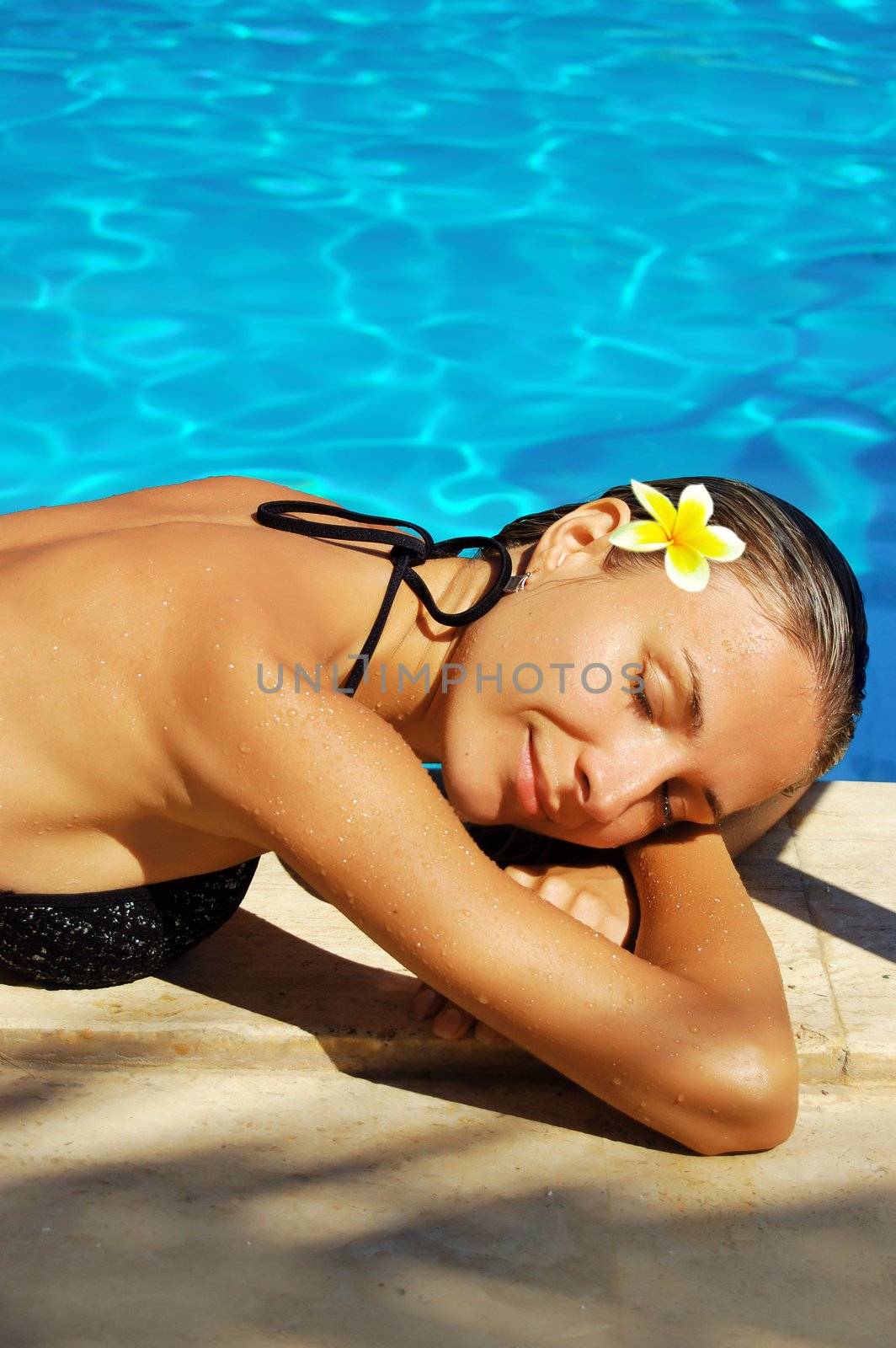 beautiful woman laying in bikini during sunbath near swimming pool