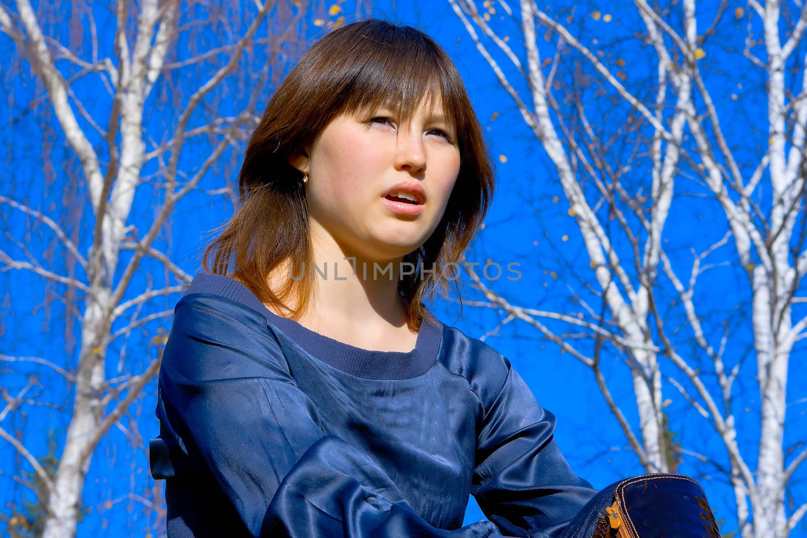 Portrait of the asian young girl against blue sky and birches