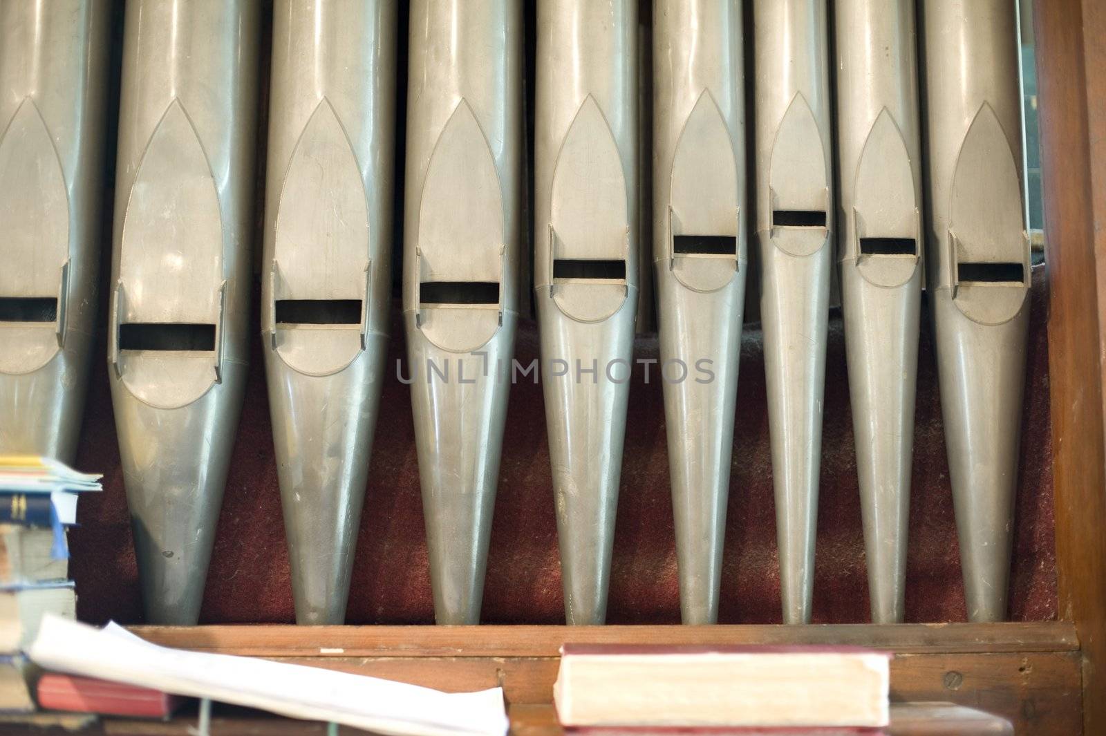 organ pipes and a pile of music book at the from of a small church organ