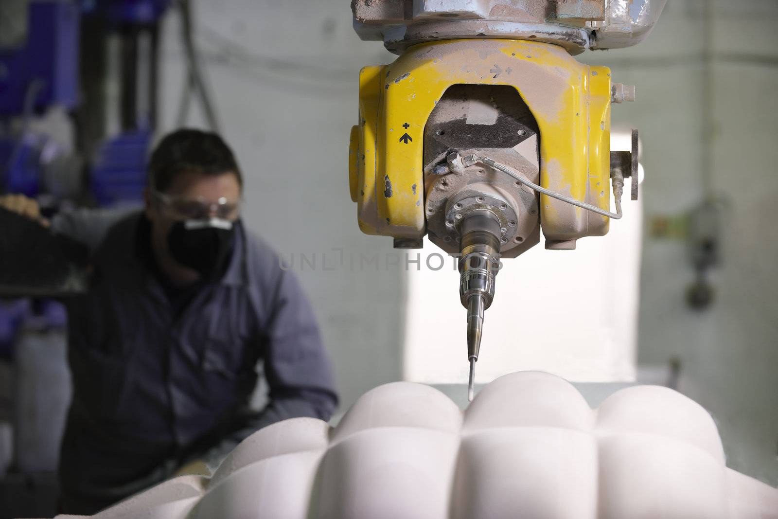 worker controlling a multi axis milling machine