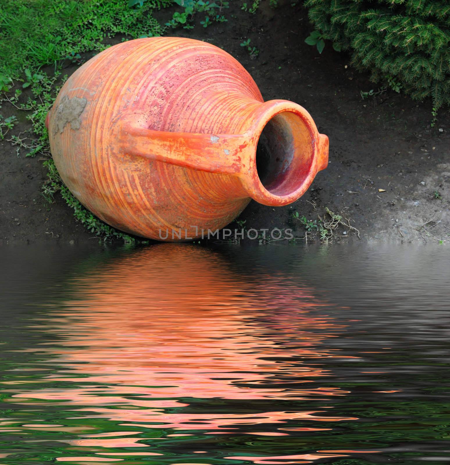 old-style greek amphora laying on earth near the water