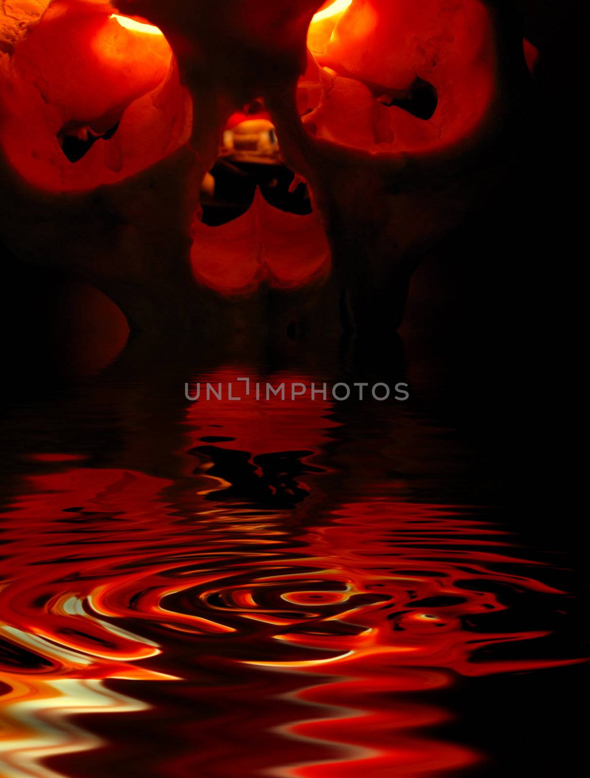 Front of burning skull - old skull against black background and reflections in water
