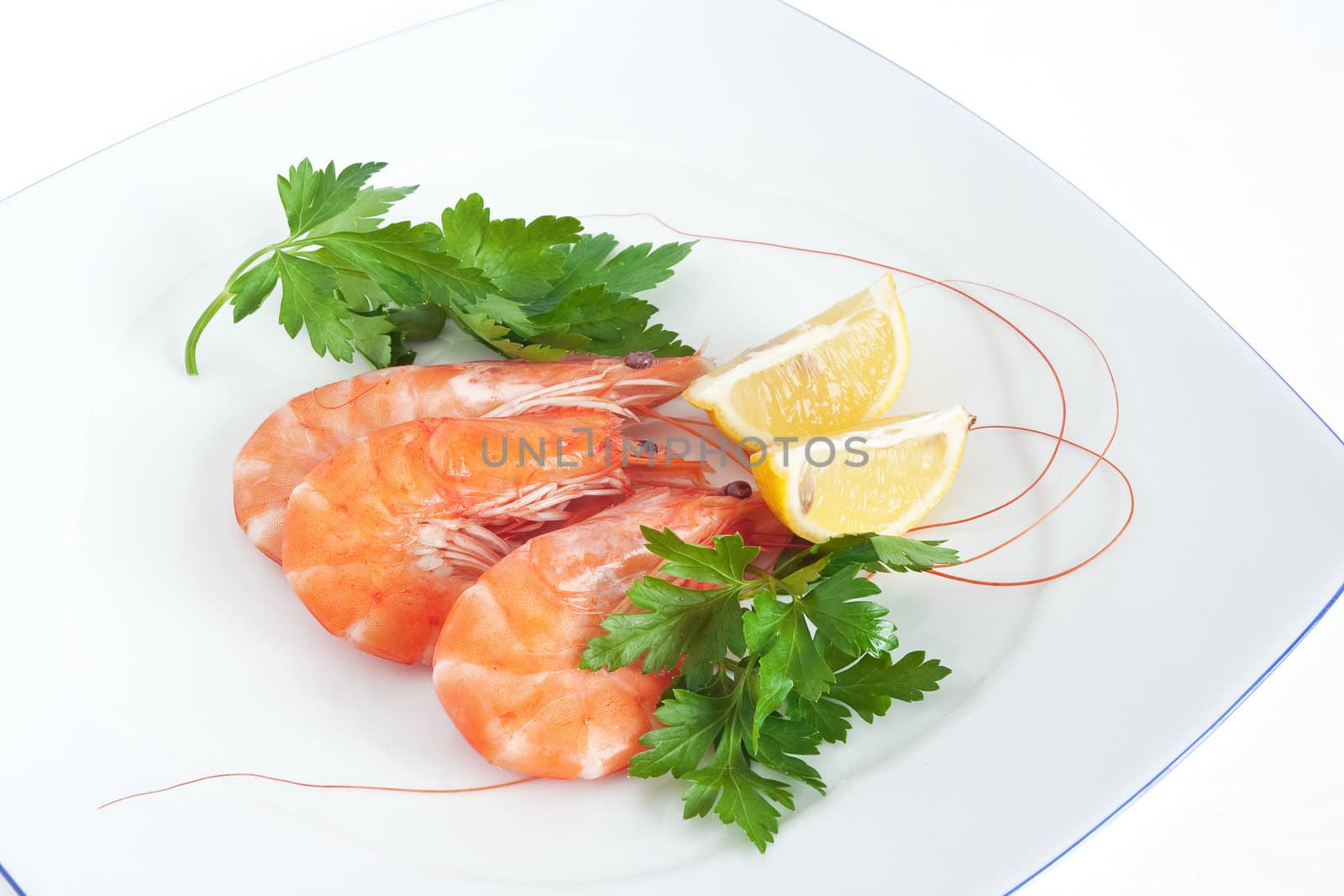 three raw prawns with lemon and parsley on a white plate isolated with clipping path