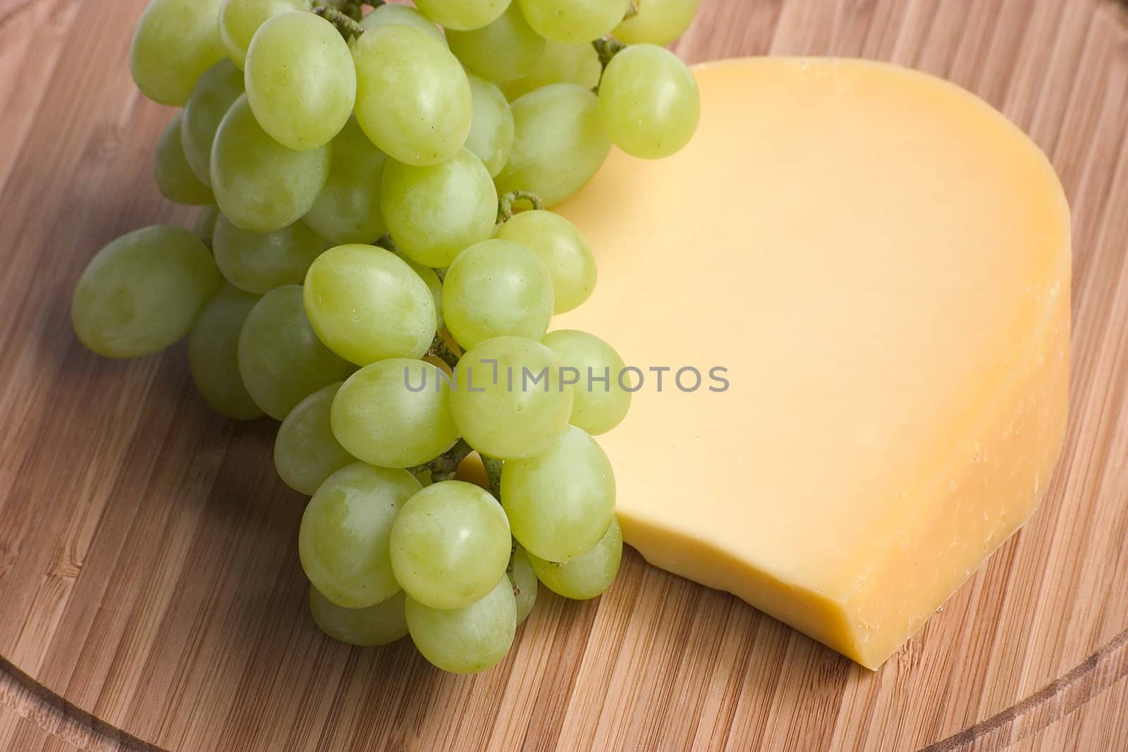 green grapes and cheese on a wooden board