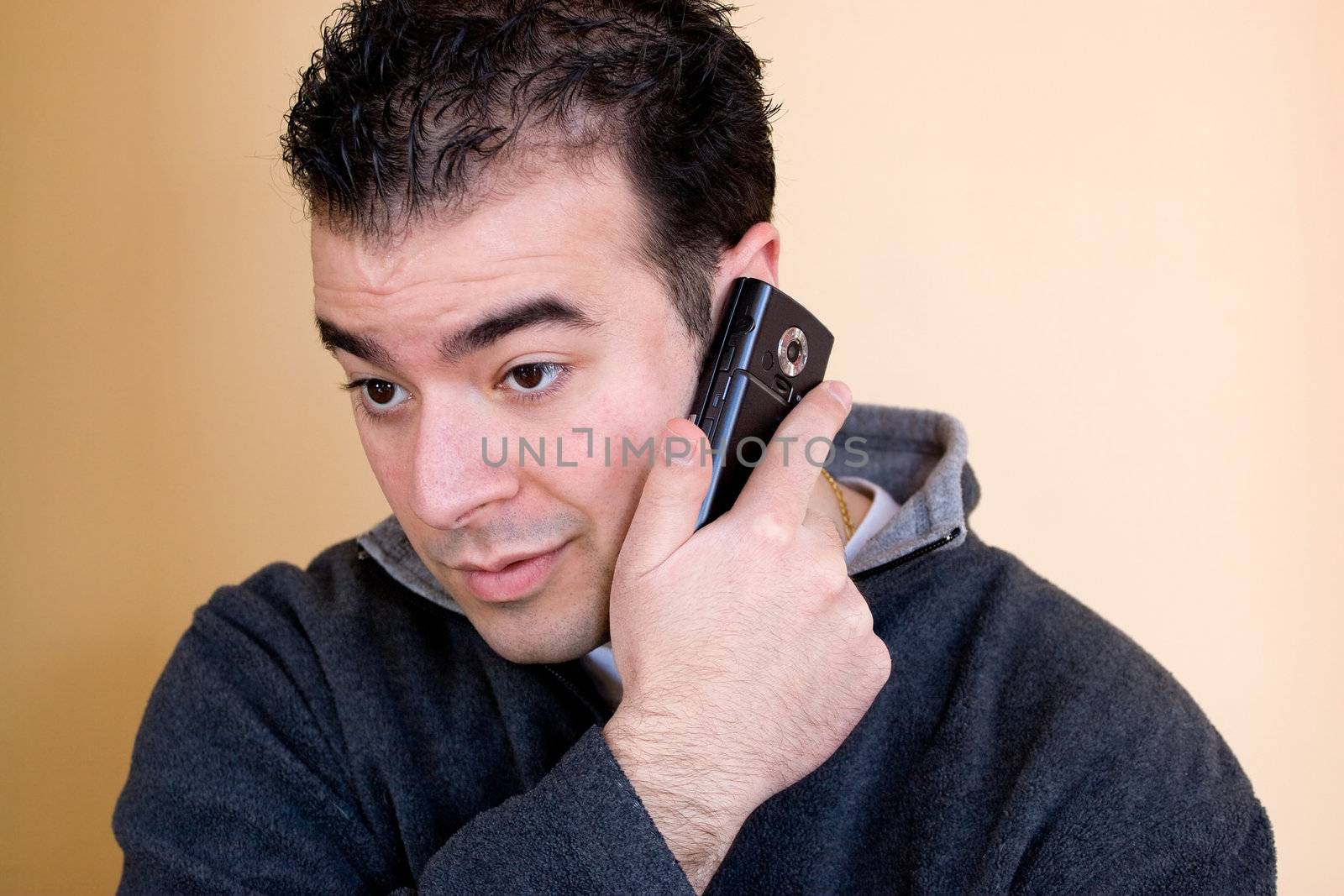 A young man talking on his cell phone.  He is holding the phone with his right hand but listening with his left ear.