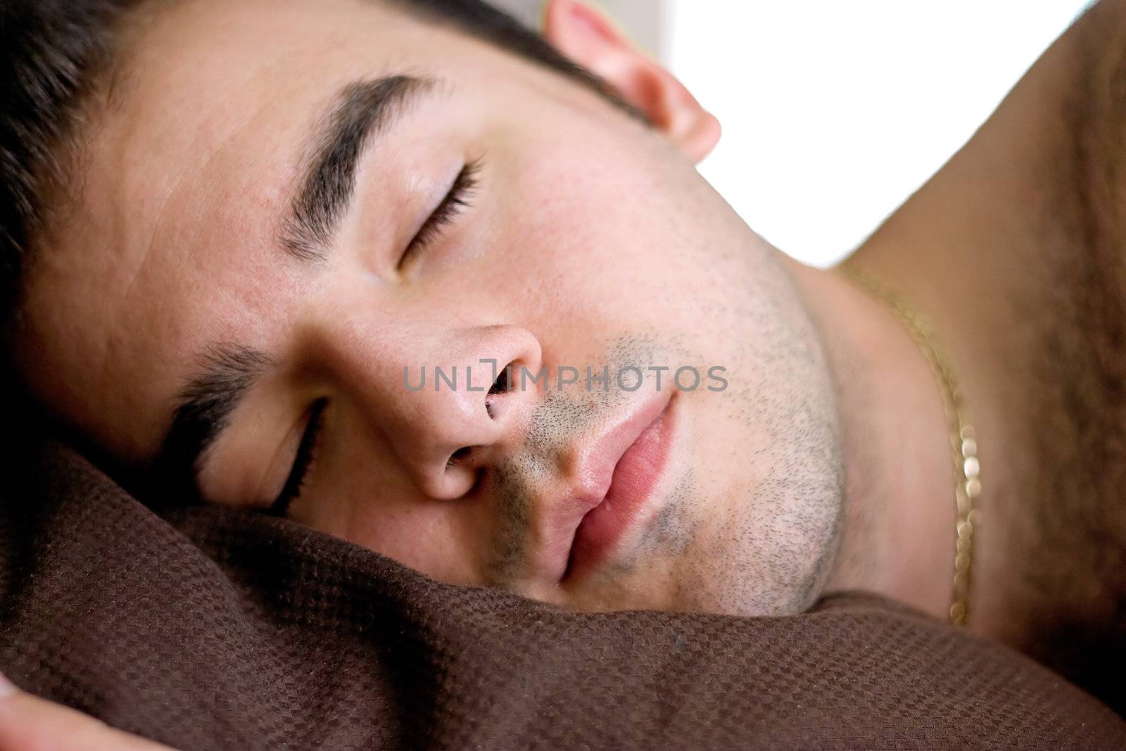A young man is fast asleep in bed.