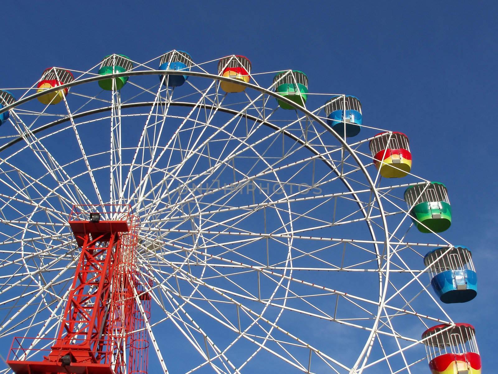 a colourful fairground wheel against a blue sky