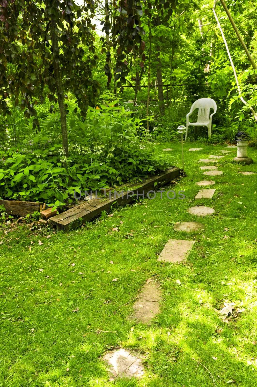 Path of stepping stones leading to secluded corner in lush green garden