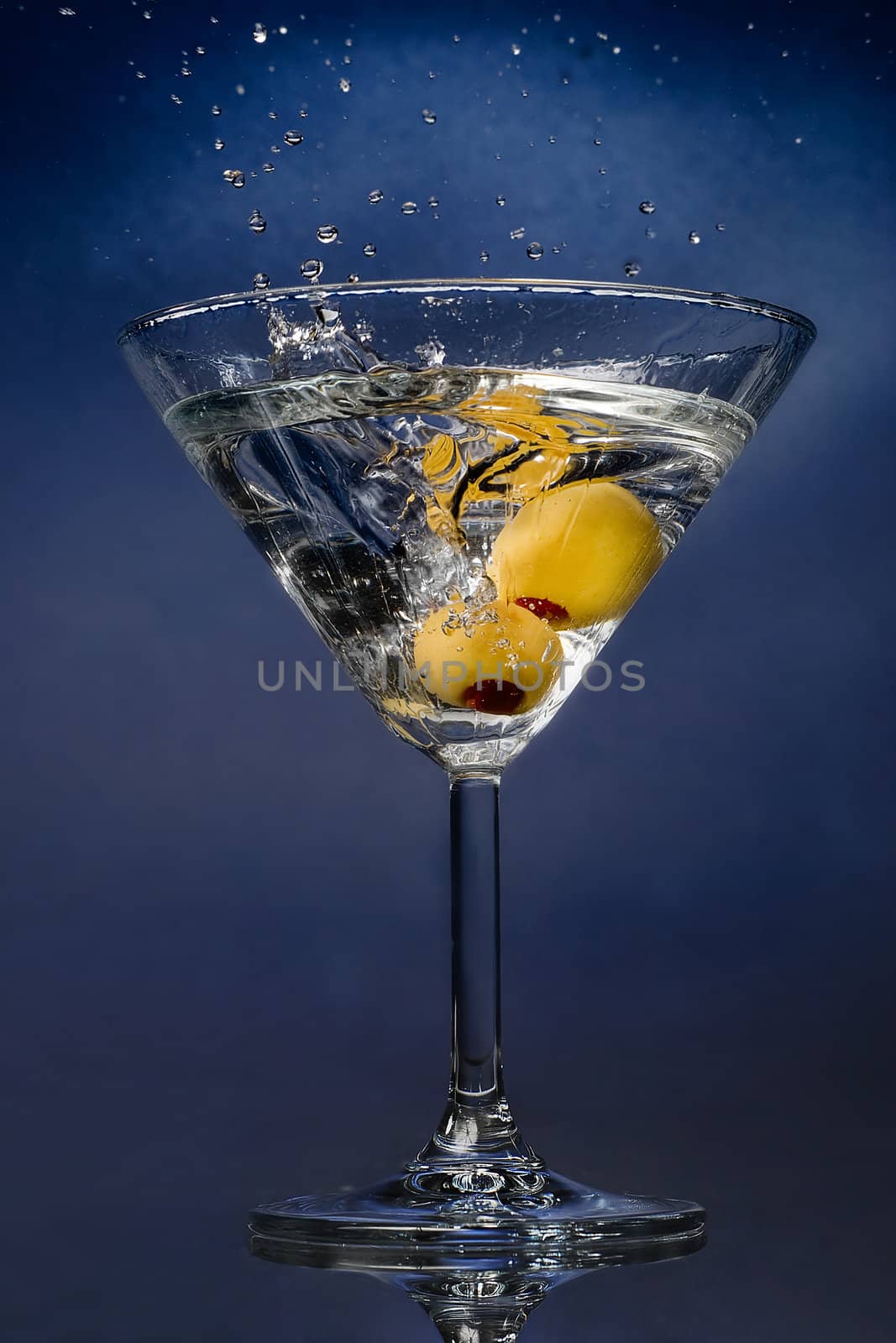 Cocktail splash with olives on blue background