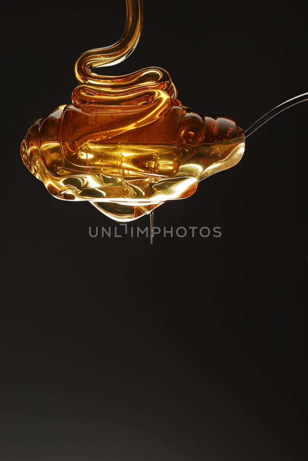 Golden honey being poured on spoon stock photo