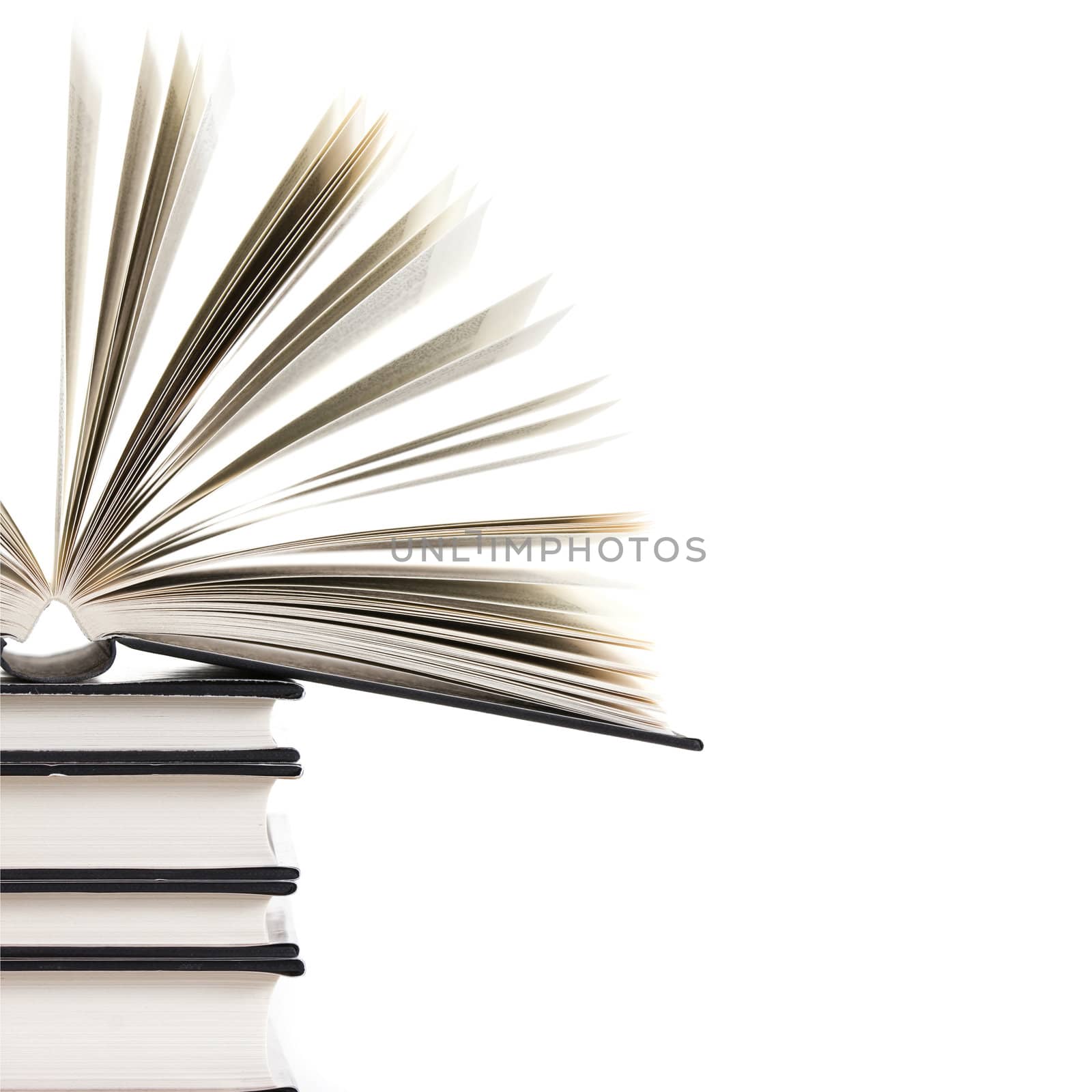 pile of books with one book open on white background 