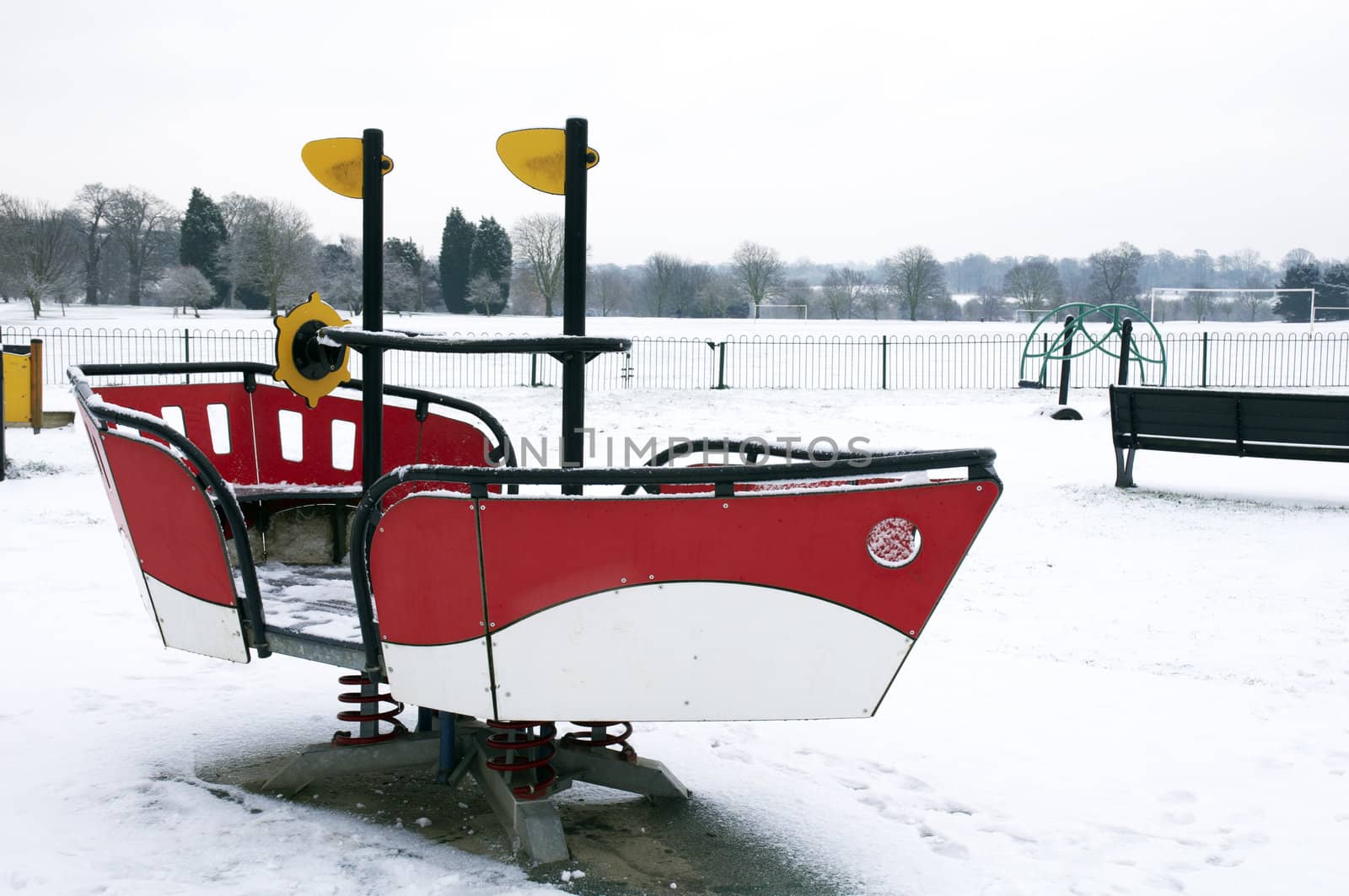 A childrens playground in a park covered in snow