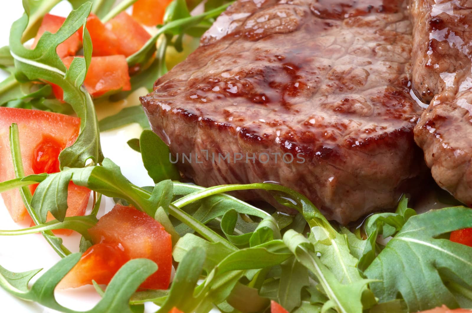 juicy fried beef steak with roocket salad and slced tomatoes