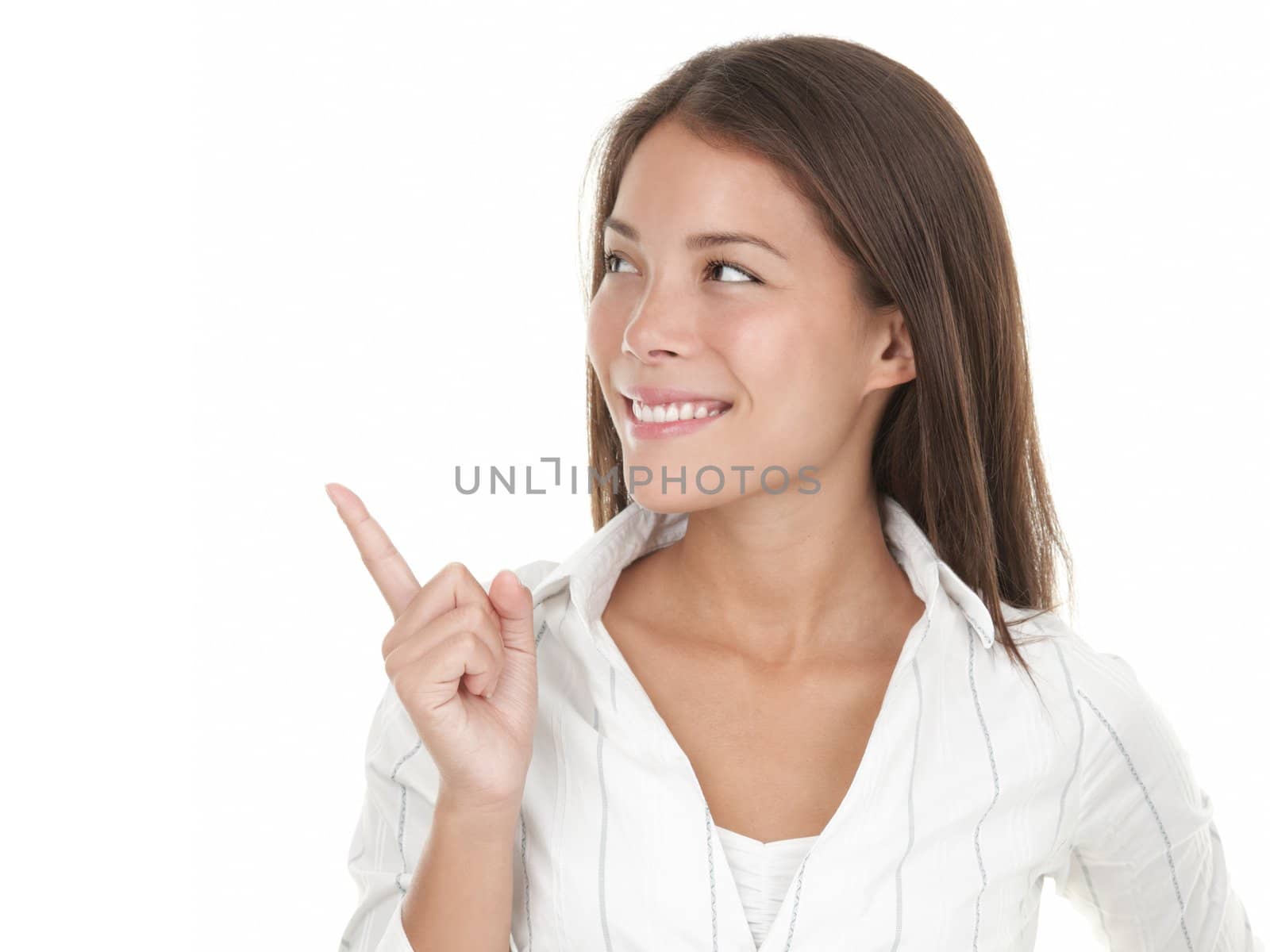 Pointing and looking to the side. Casual young businesswoman in white shirt looking, pointing and smiling at copy space. Beautiful young mixed race chinese / caucasian woman isolated on white.