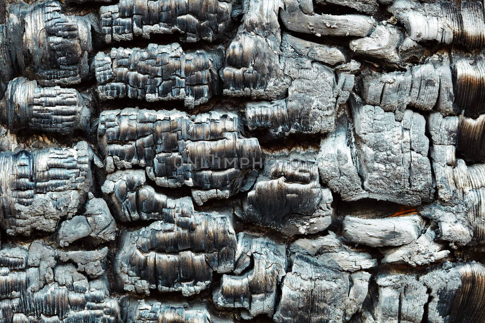 The charred wooden black wall after a fire