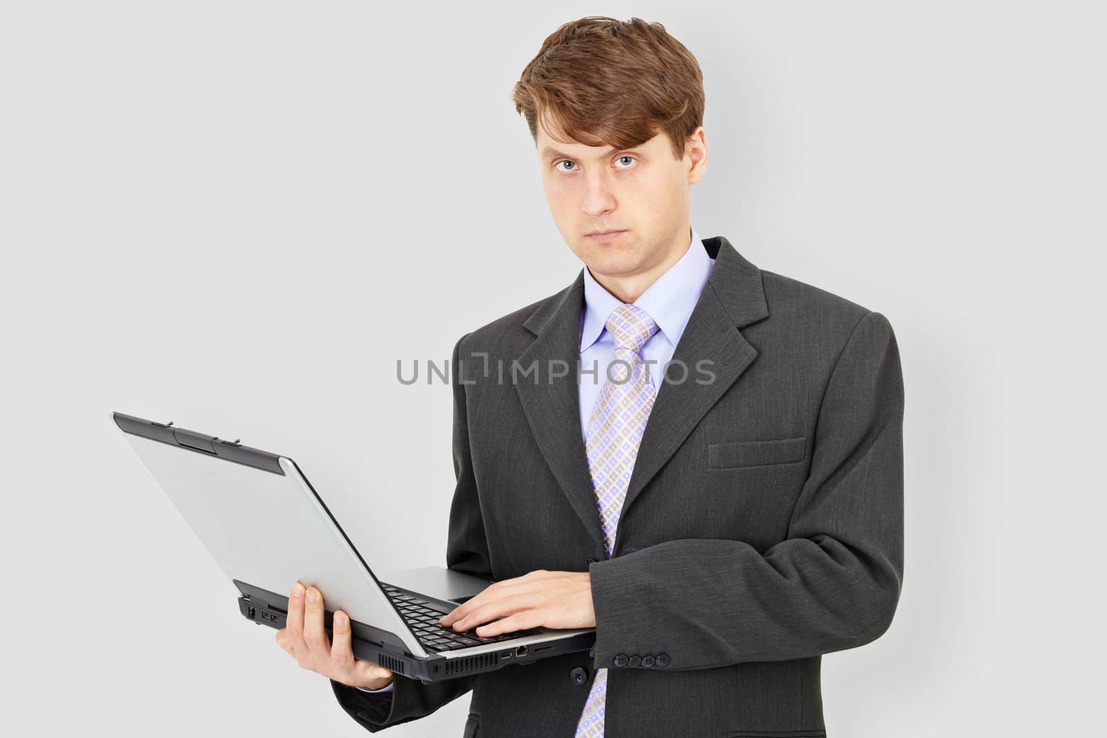 Business man with laptop on grey background by pzaxe